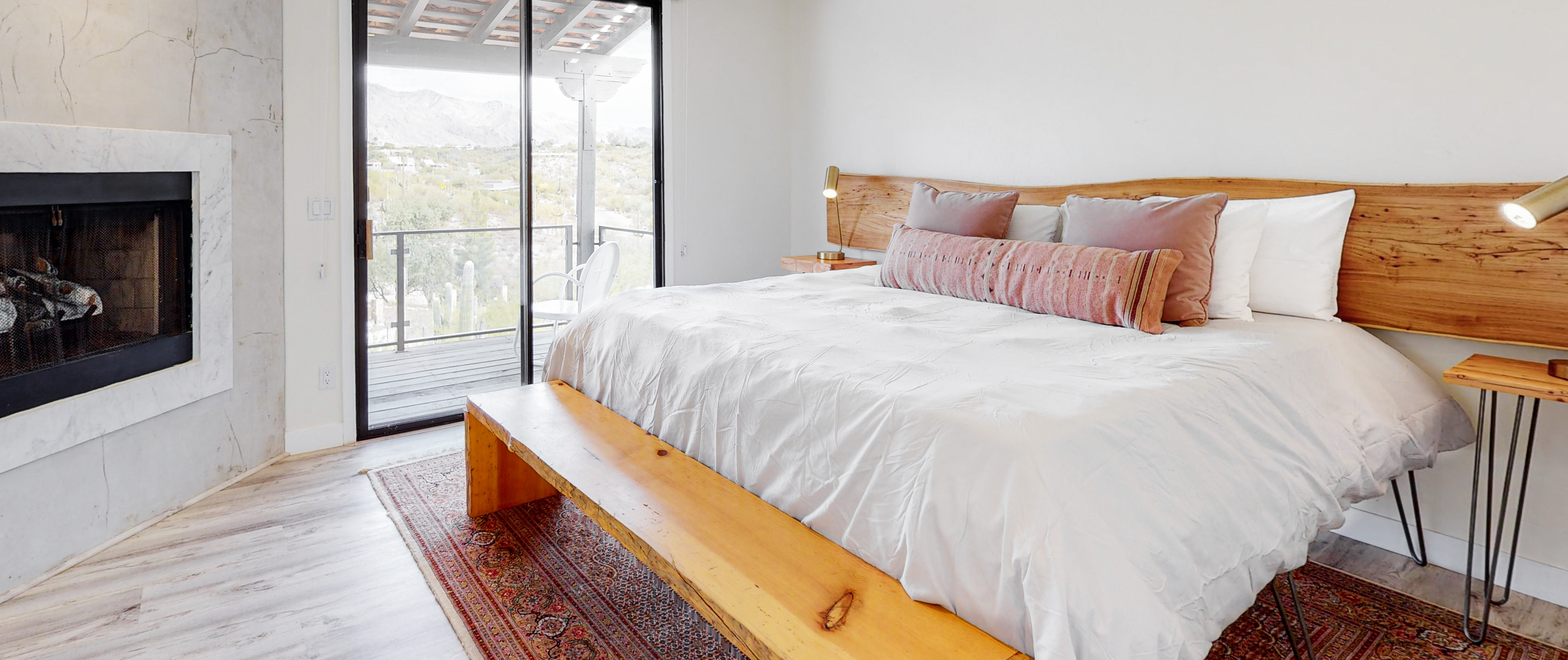 Inside a Tucson, AZ vacation rental bedroom with a white bed, wooden style furniture and fireplace.