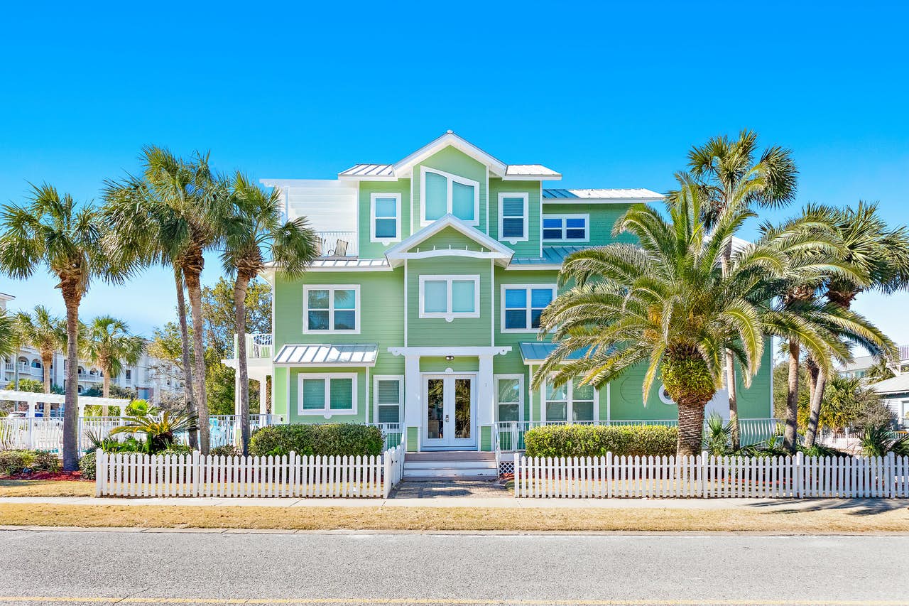seafoam green vacation home surrounded by palm trees