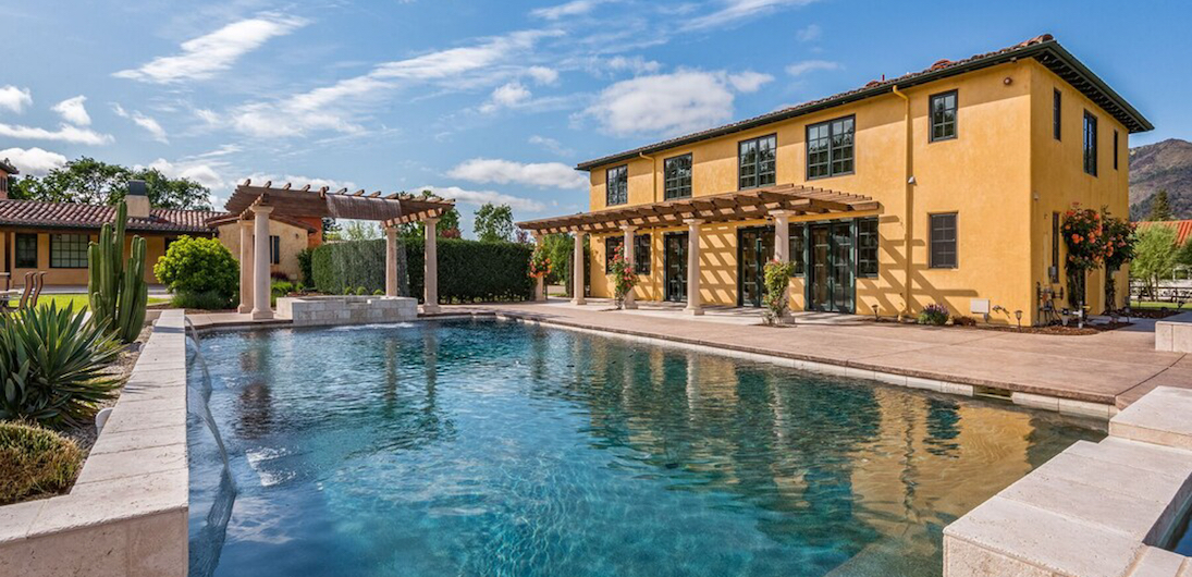 Yellow stucco vacation home in California with outdoor pool surrounded by cacti
