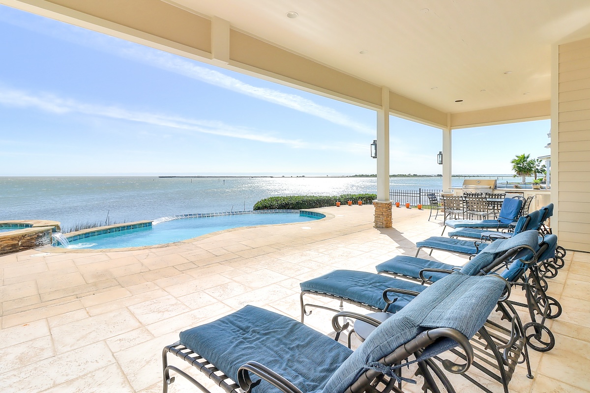 The deck with chairs and a pool overlooking the ocean at a Rockport, TX rental.