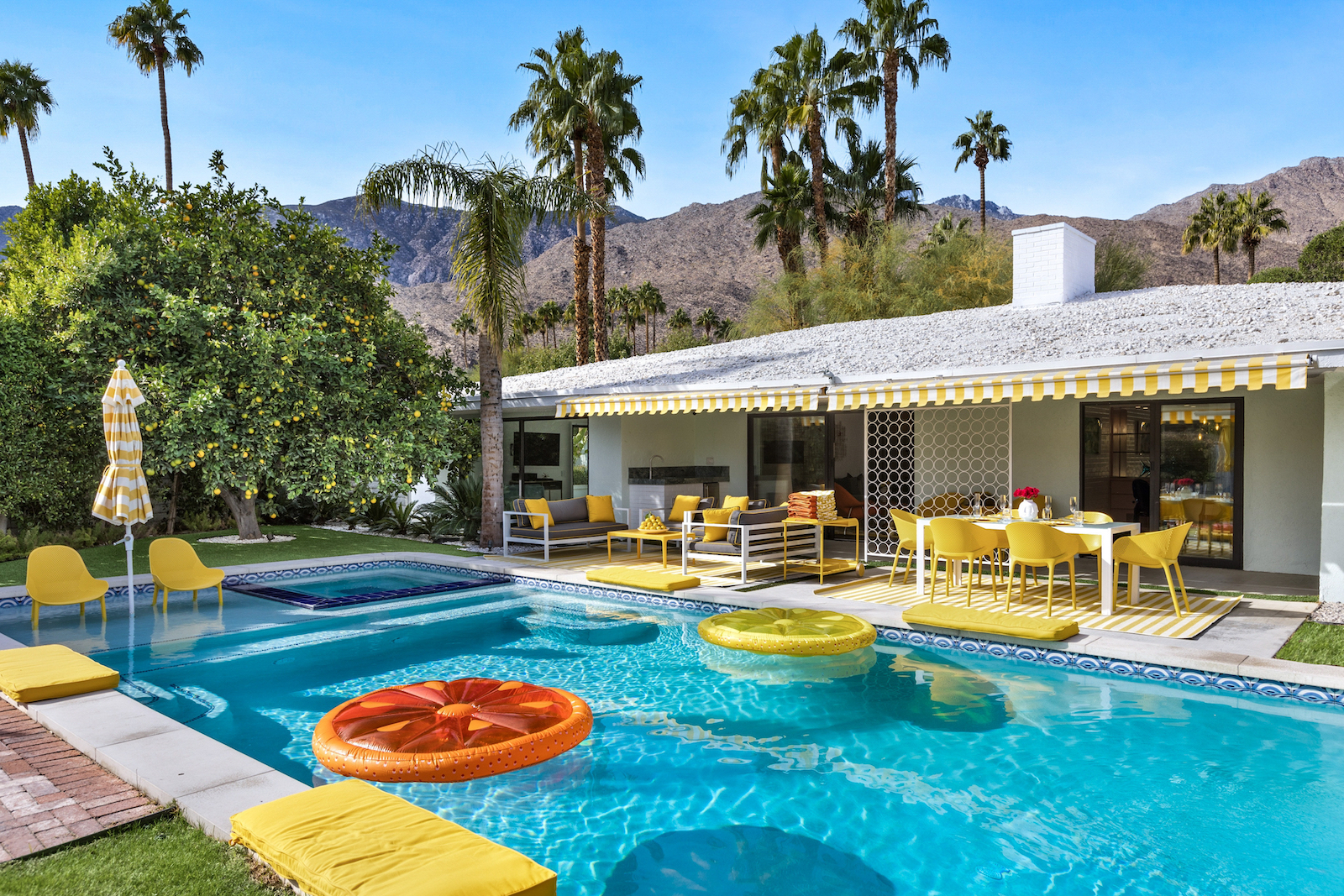 The pool area with colorful furniture and floaties at a vacation rental in Palm Springs, CA.