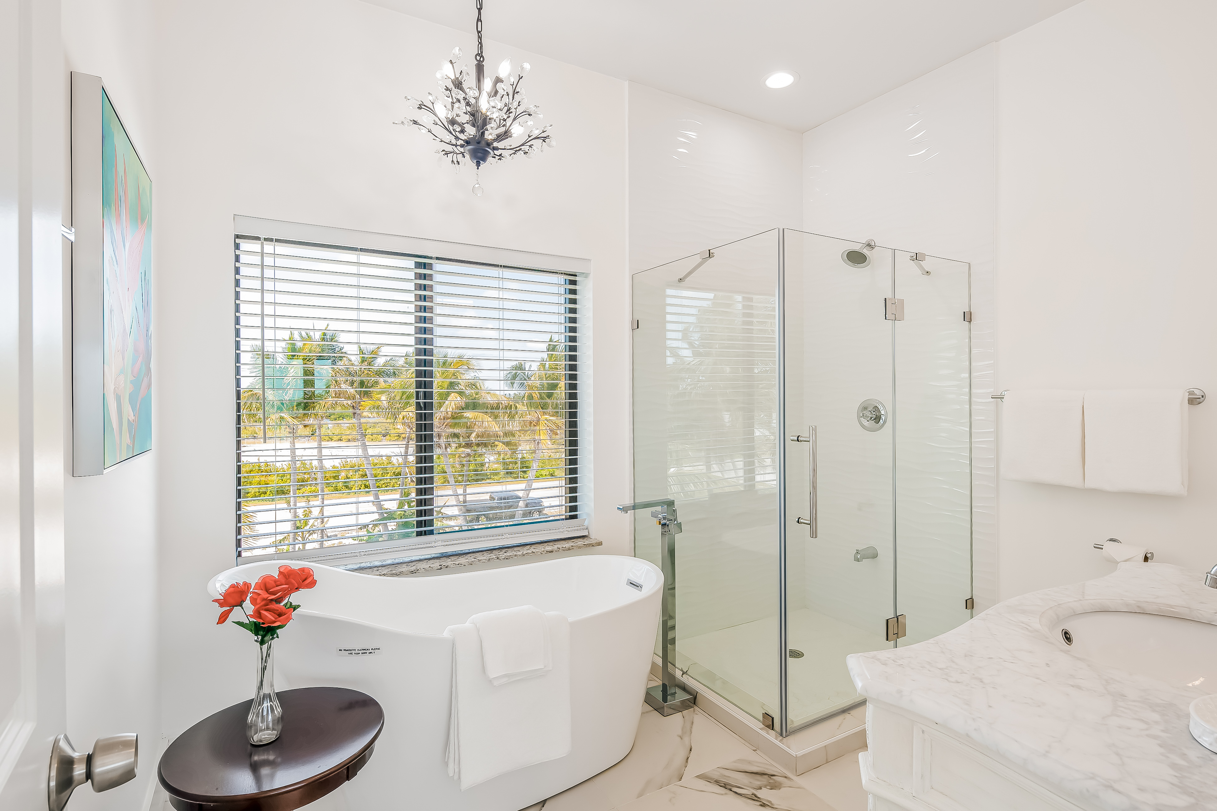 a vase of red flowers really pops in this sleek white bathroom