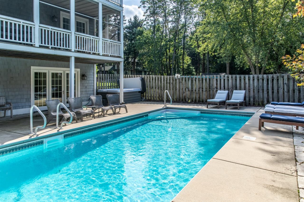 An outdoor pool and outdoor hot tub with lounger chairs at a vacation home rental in Lake Michigan.