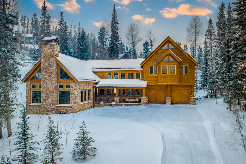 The exterior of a large cabin rental surrounded by snow in Mountain Village, CO.
