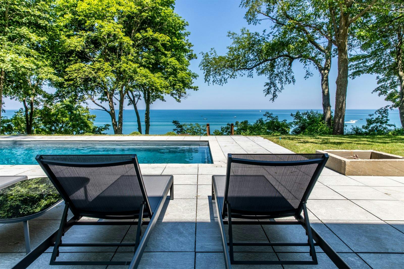 Lounge chairs sit next to outdoor pool facing Lake Michigan