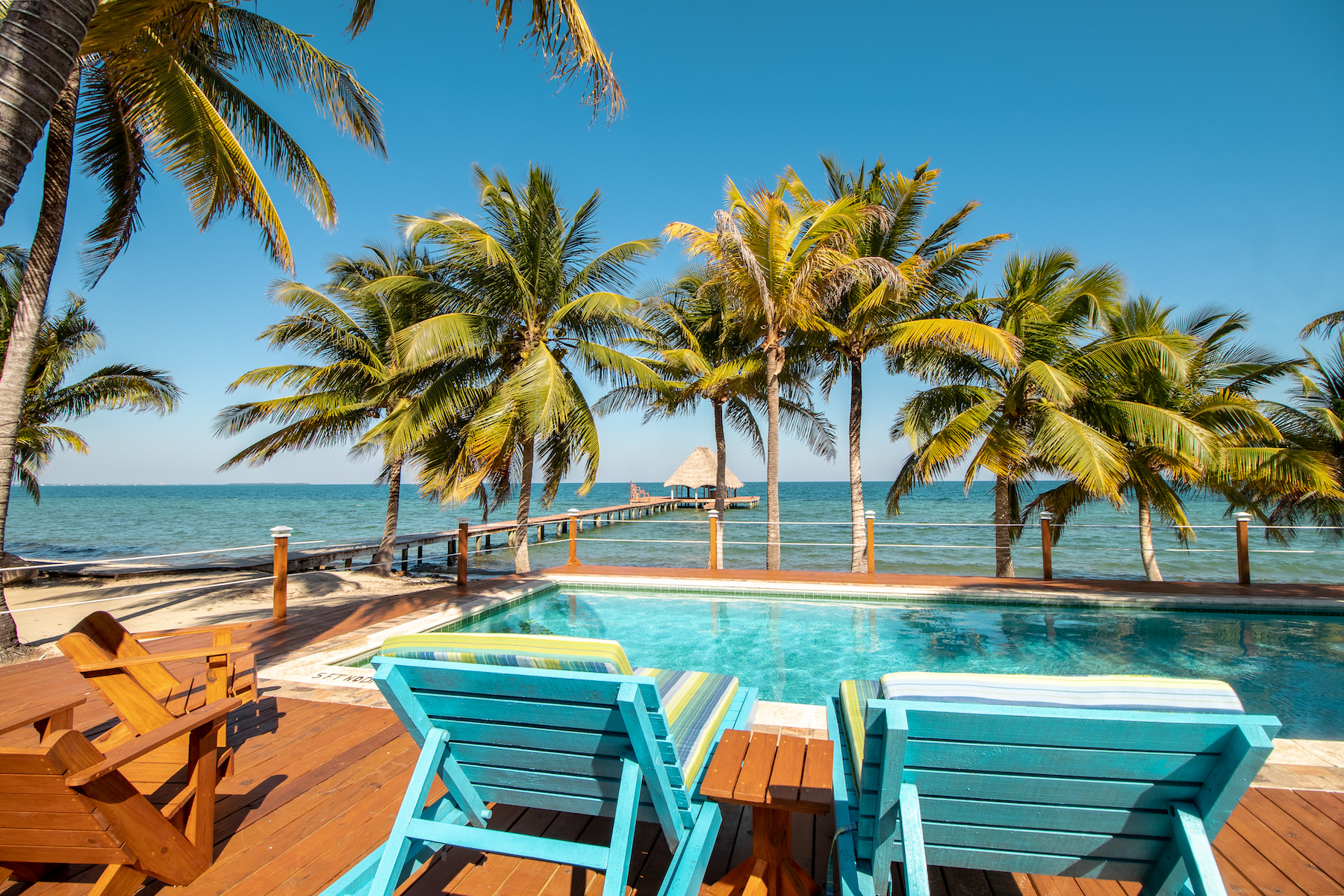 Deck chairs near a pool overlooking the ocean at a Belize vacation rental.
