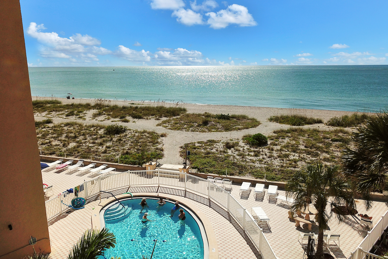 The view from the deck of a vacation rental condo in Venice, FL overlooking the ocean and a resort pool.