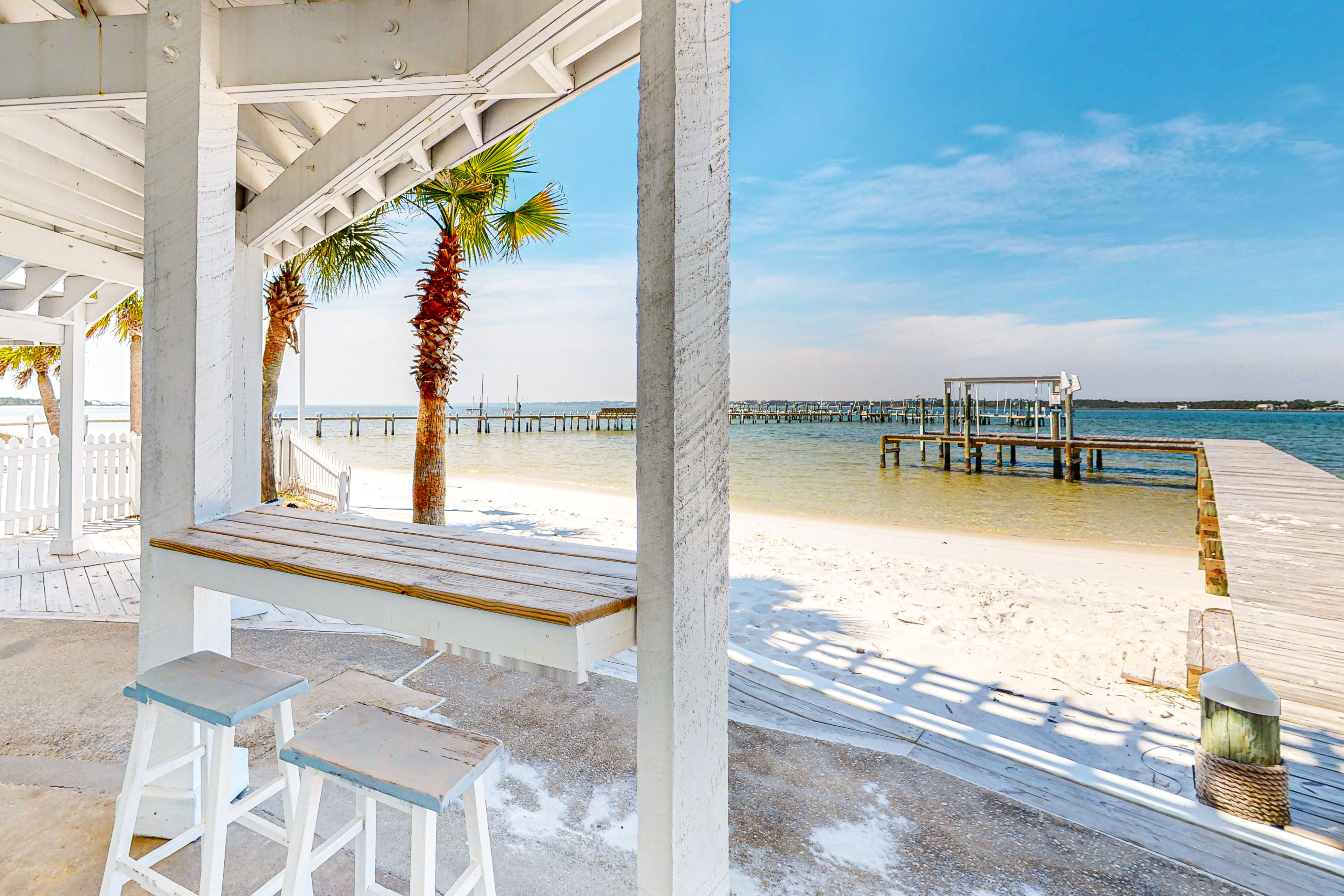 counter table with two chairs overlooks sandy beach and dock under navarre florida vacation home