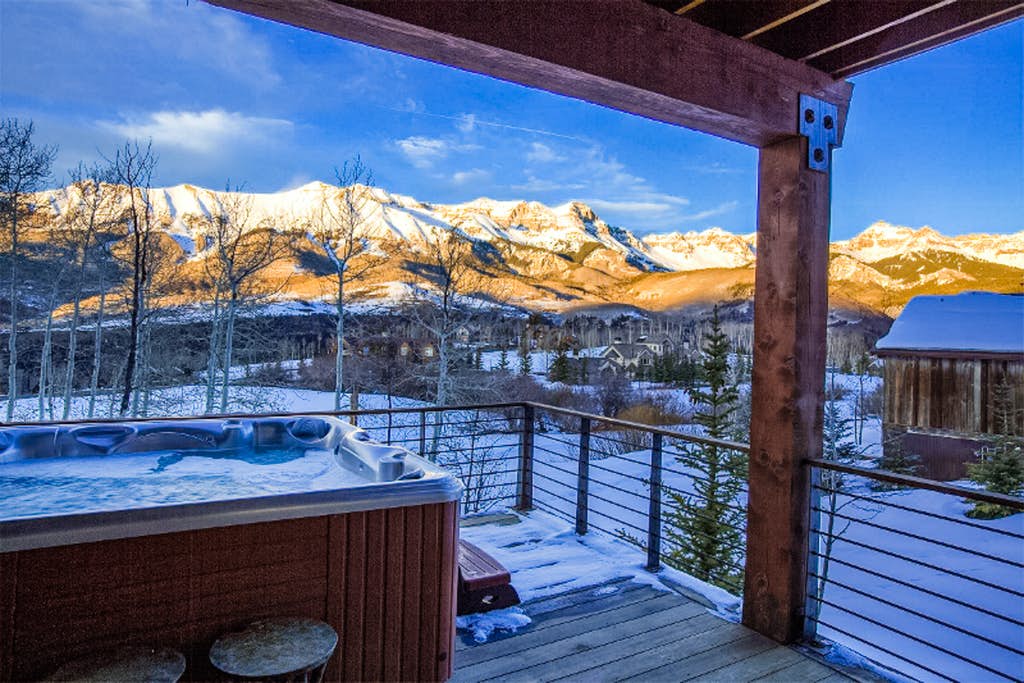 Outdoor hot tub on a deck of a vacation home in Telluride, CO with a view of snowy mountains.