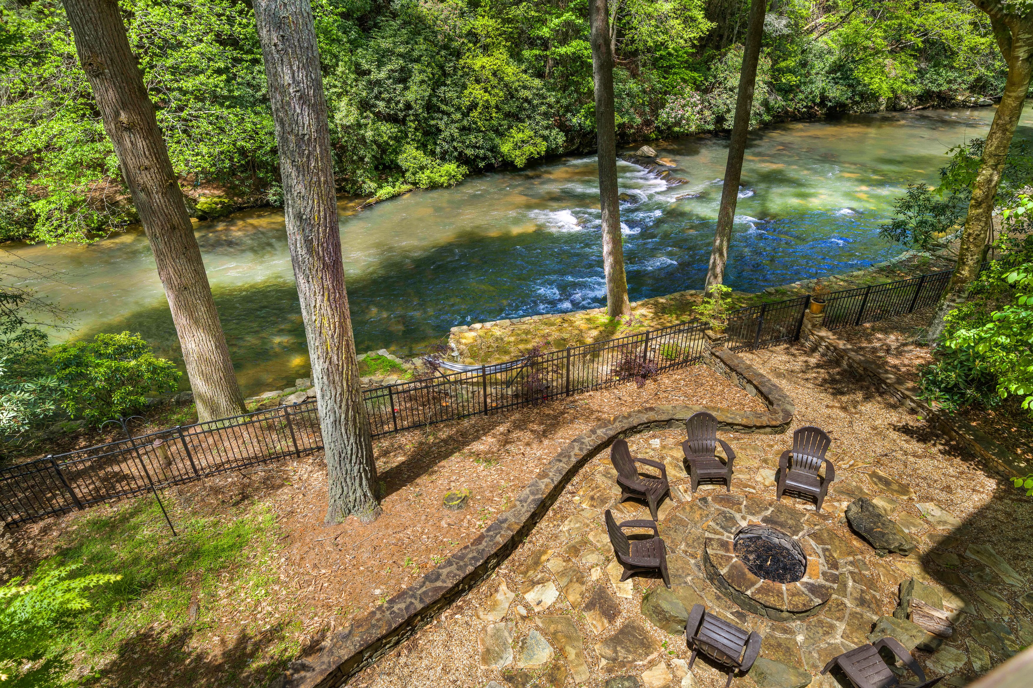 aerial view of backyard of vacation home with a rushing river and a firepit with seating
