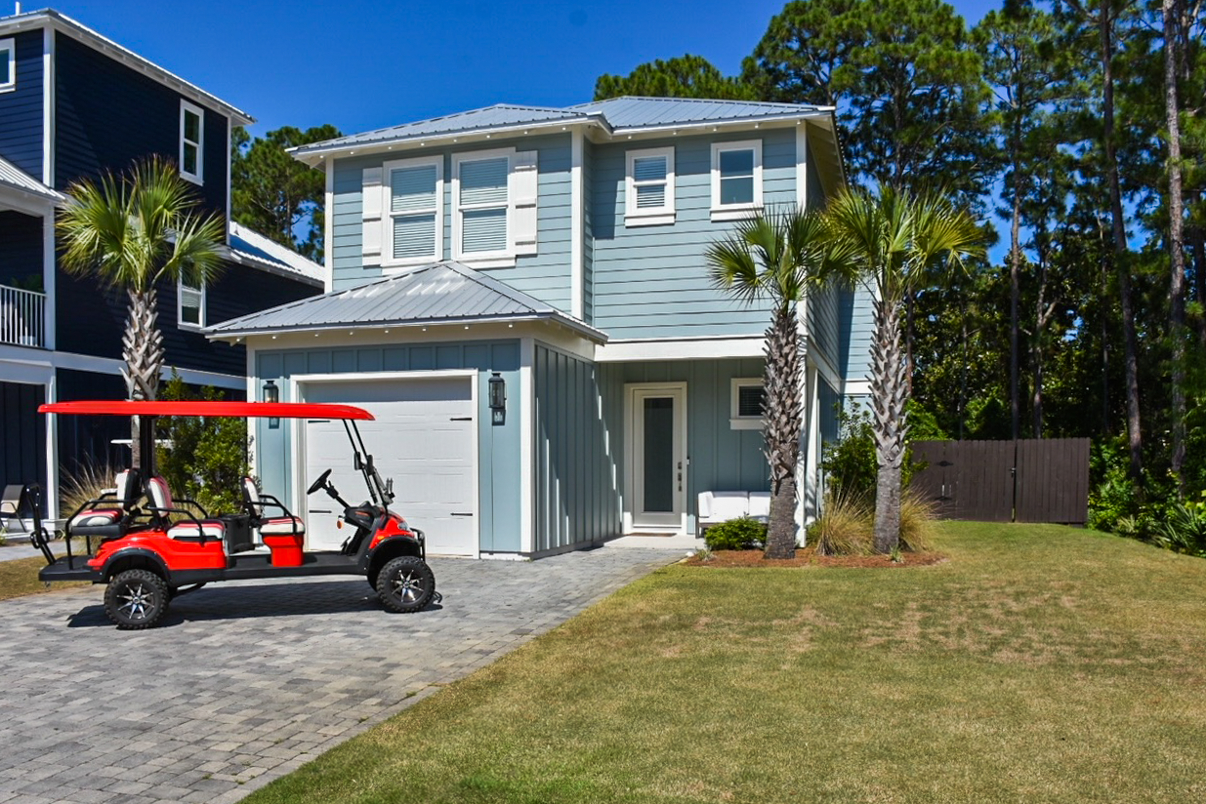 red golf cart in driveway of light blue vacation home in florida