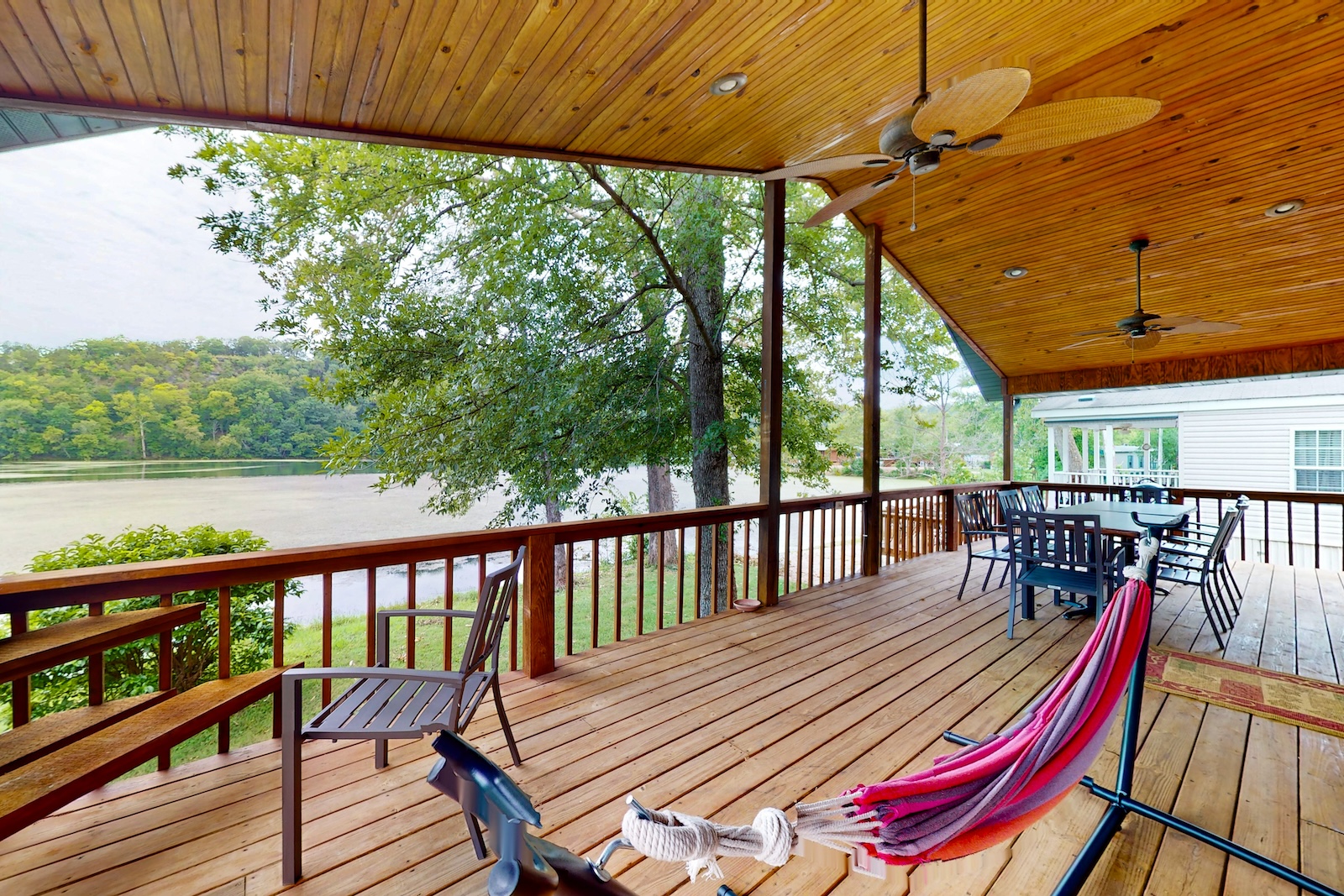 Back patio with chairs, hammock, and more overlooking the water at a cabin rental in Forsyth.
