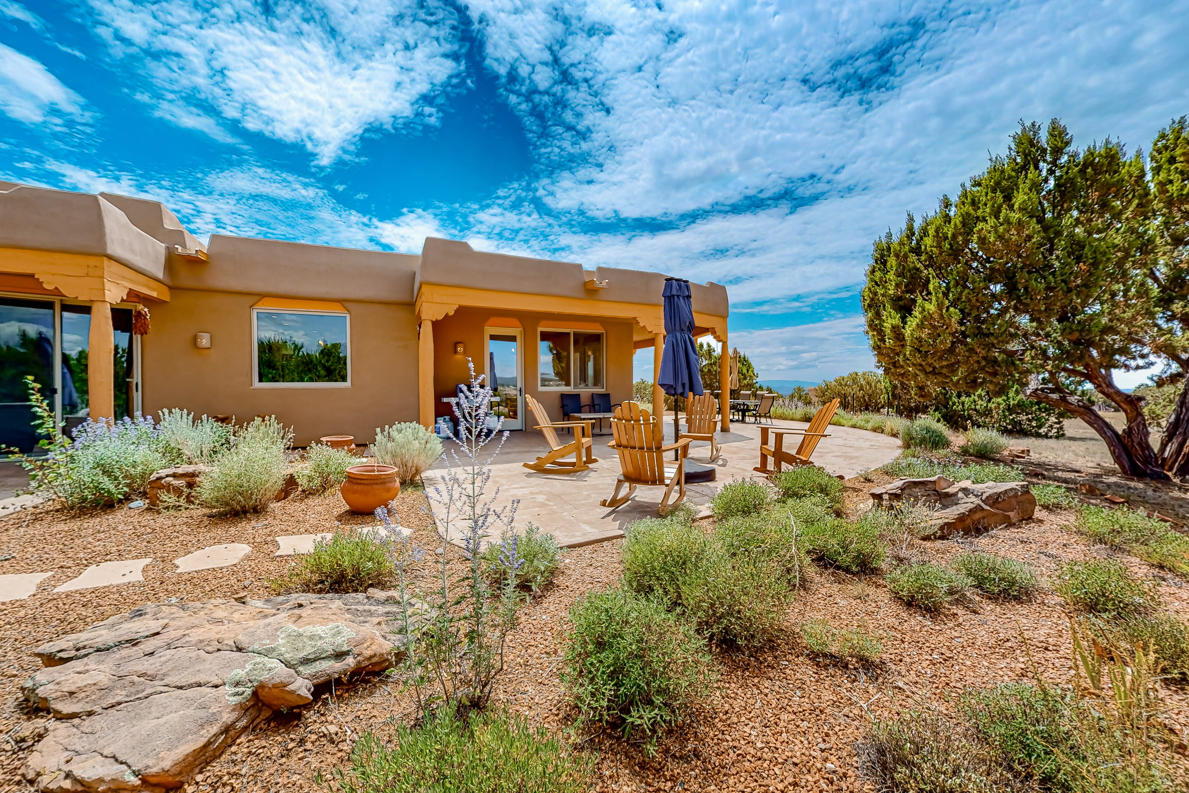 santa fe adobe style home with landscaped yard and backyard sitting area