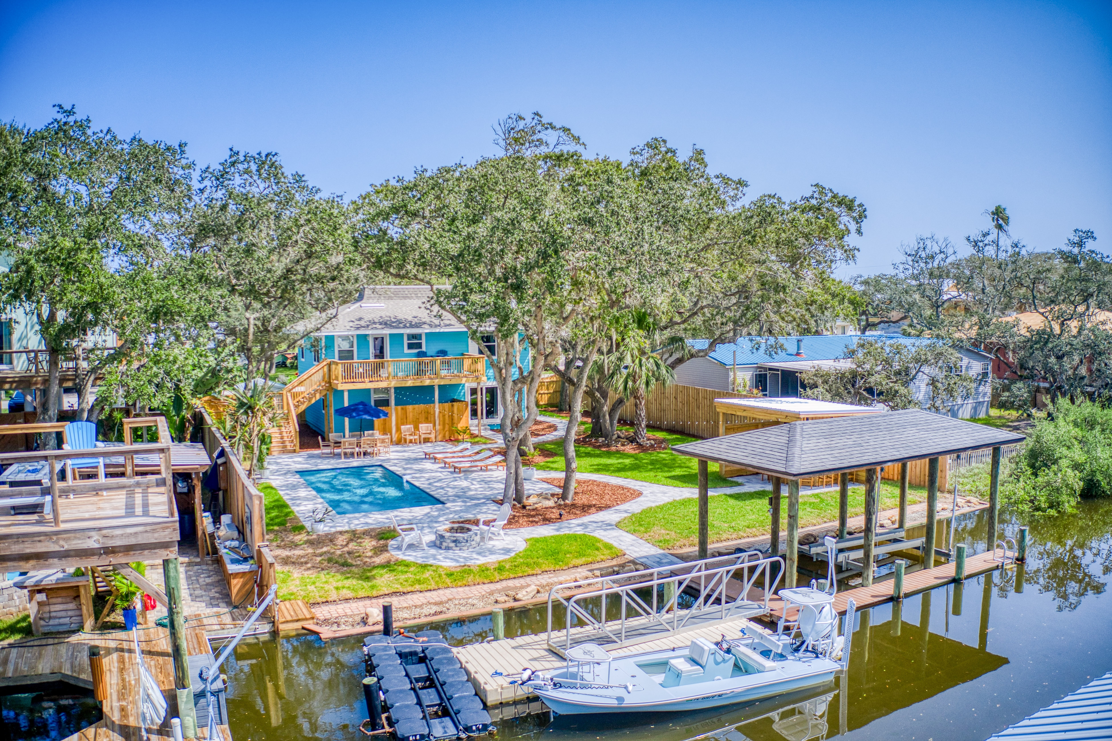 blue waterfront vacation home with outdoor pool, dock, and boat