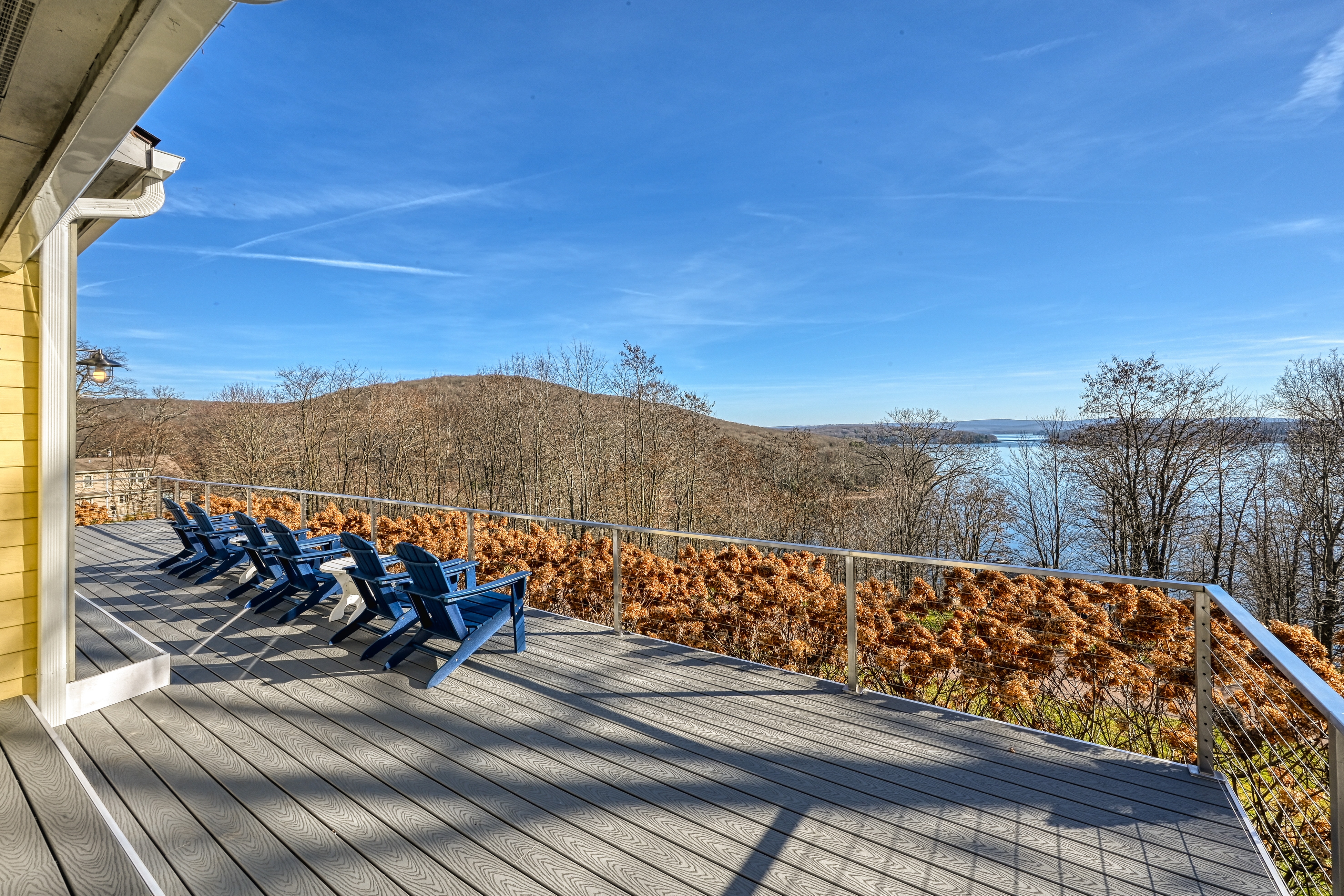 six blue adirondack chairs sit on back deck of lake home on looking out over deep creek lake in winter