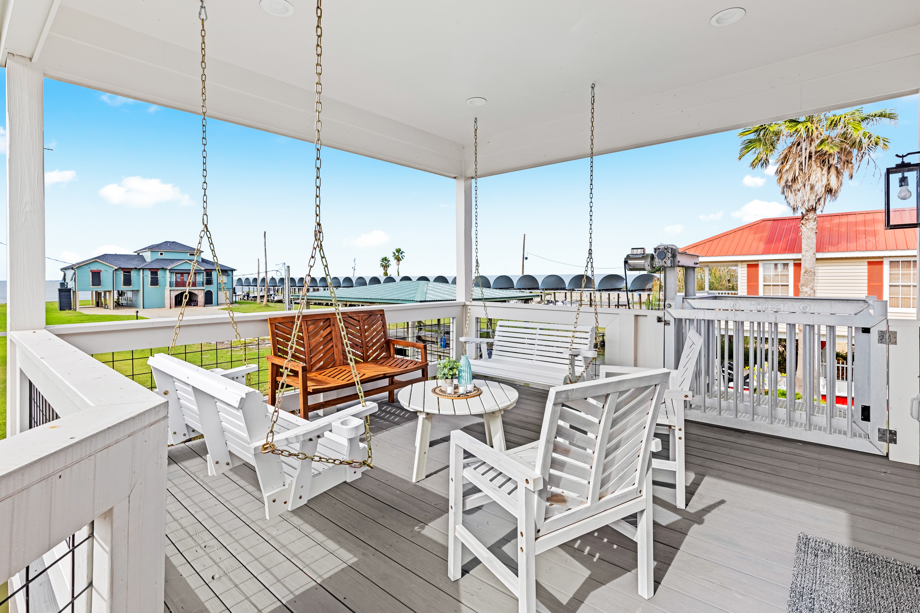 cozy covered porch with hanging benches and chairs looking out toward the lake