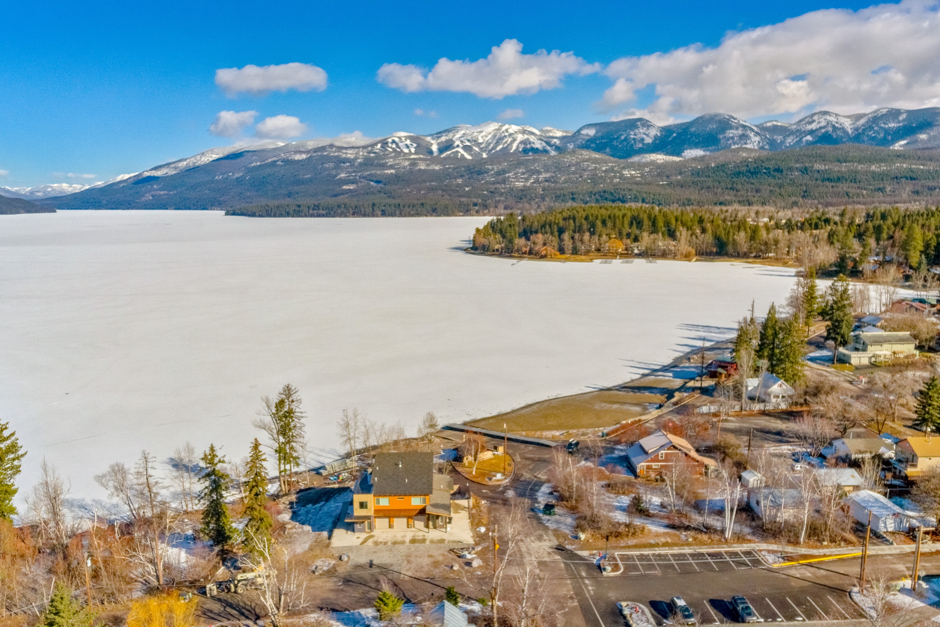 lakefront homes surround a frozen lake in whitefish, montana