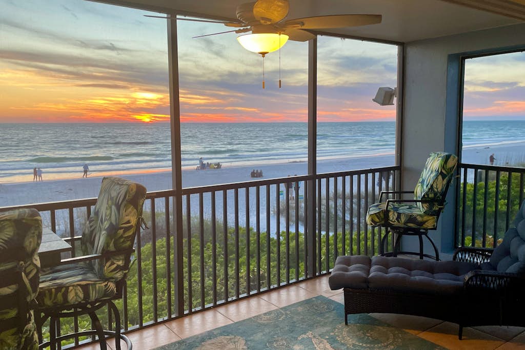 Enclosed back porch with an oceanfront view during sunset