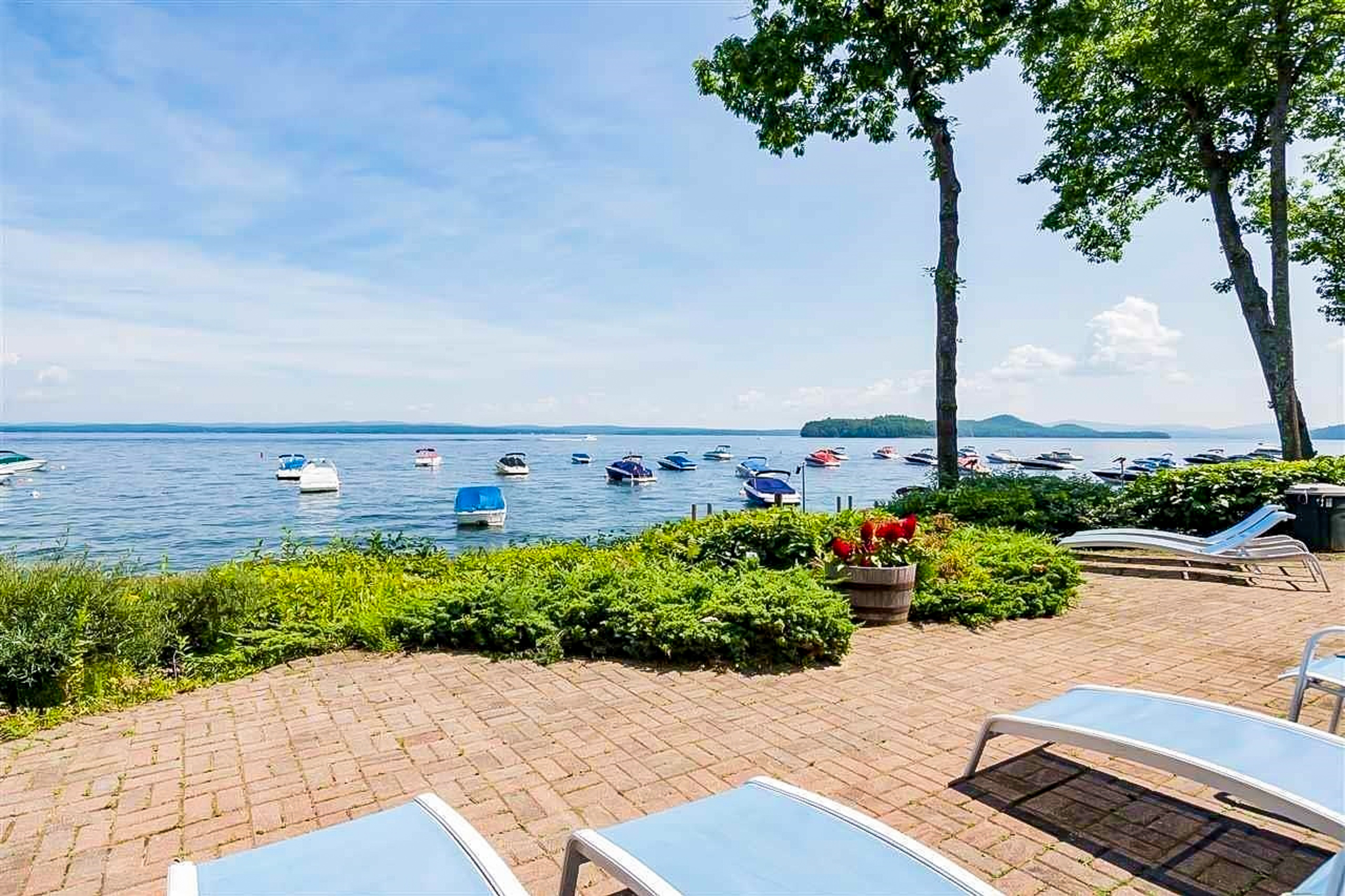 lounge chairs face several boats anchored on Lake Winnipesaukee on a summer day