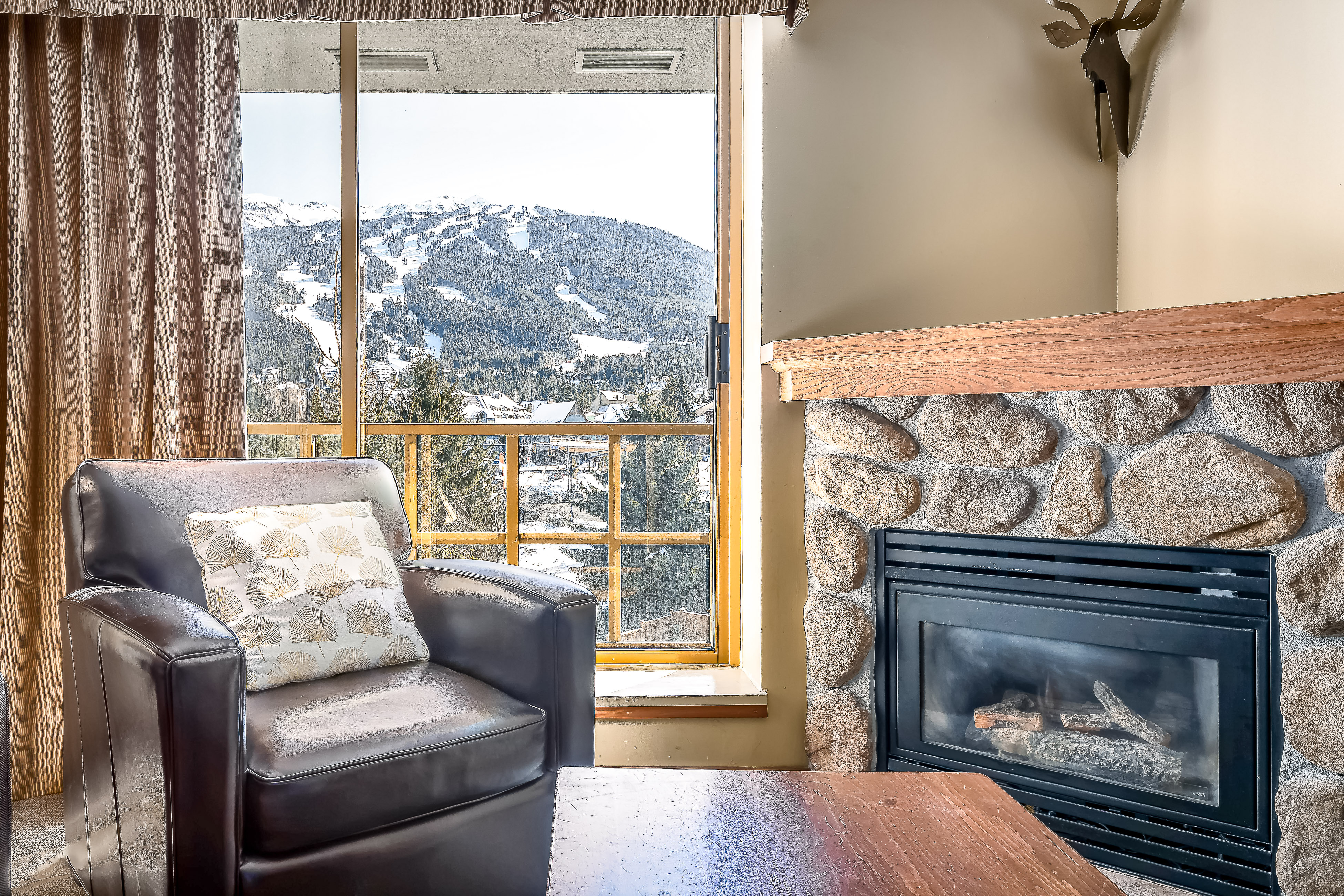 Indoor fireplace in a living room with a view of the mountains from a patio