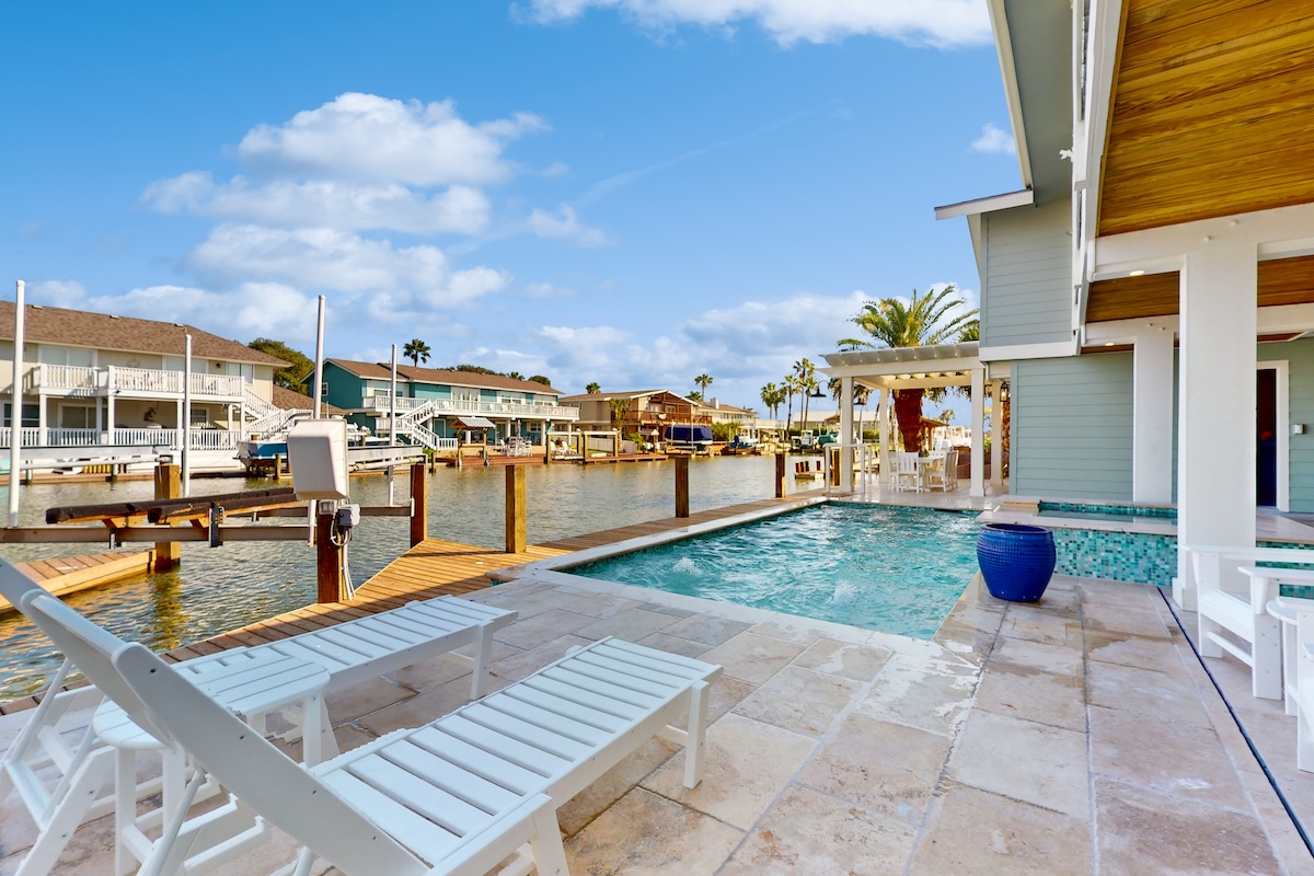 A back area with a pool, chairs, and a canal.