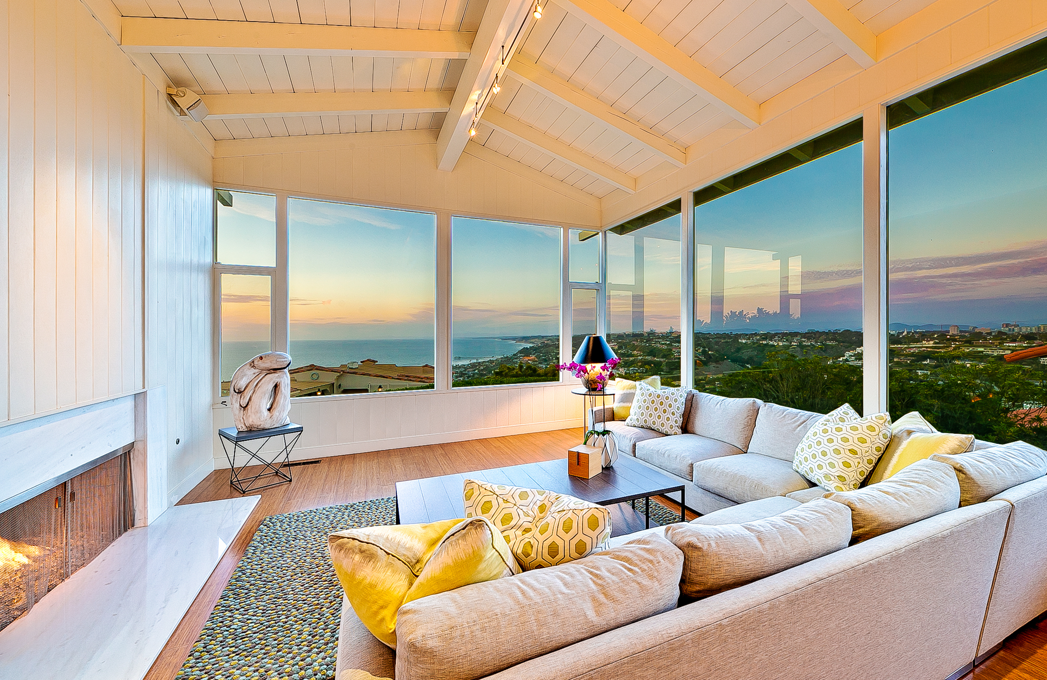 Bright colored modern living room with a fire place and large panoramic windows in La Jolla, CA