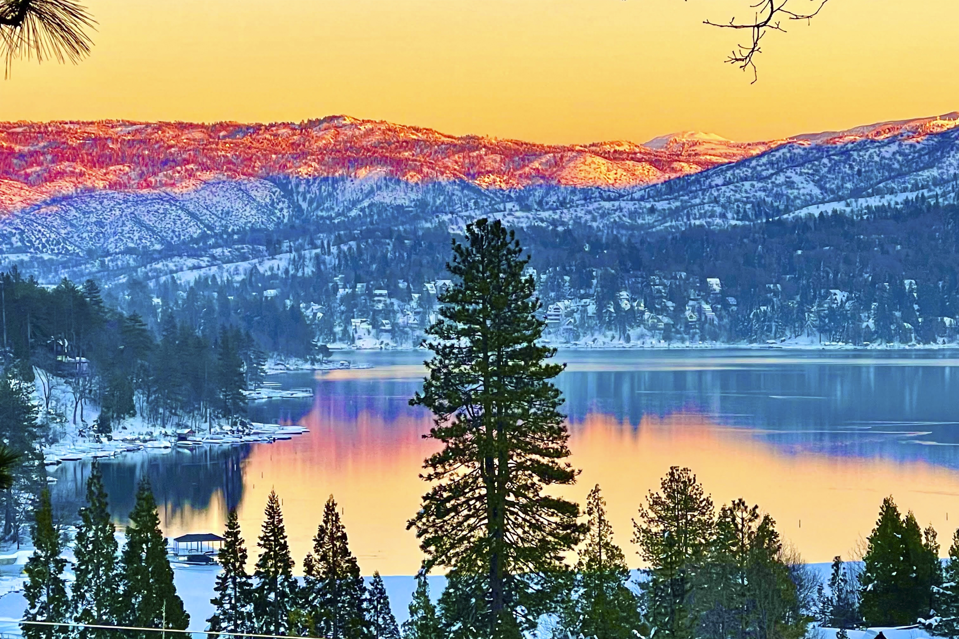 a view of lake arrowhead, ca in winter dusted with snow at sunset