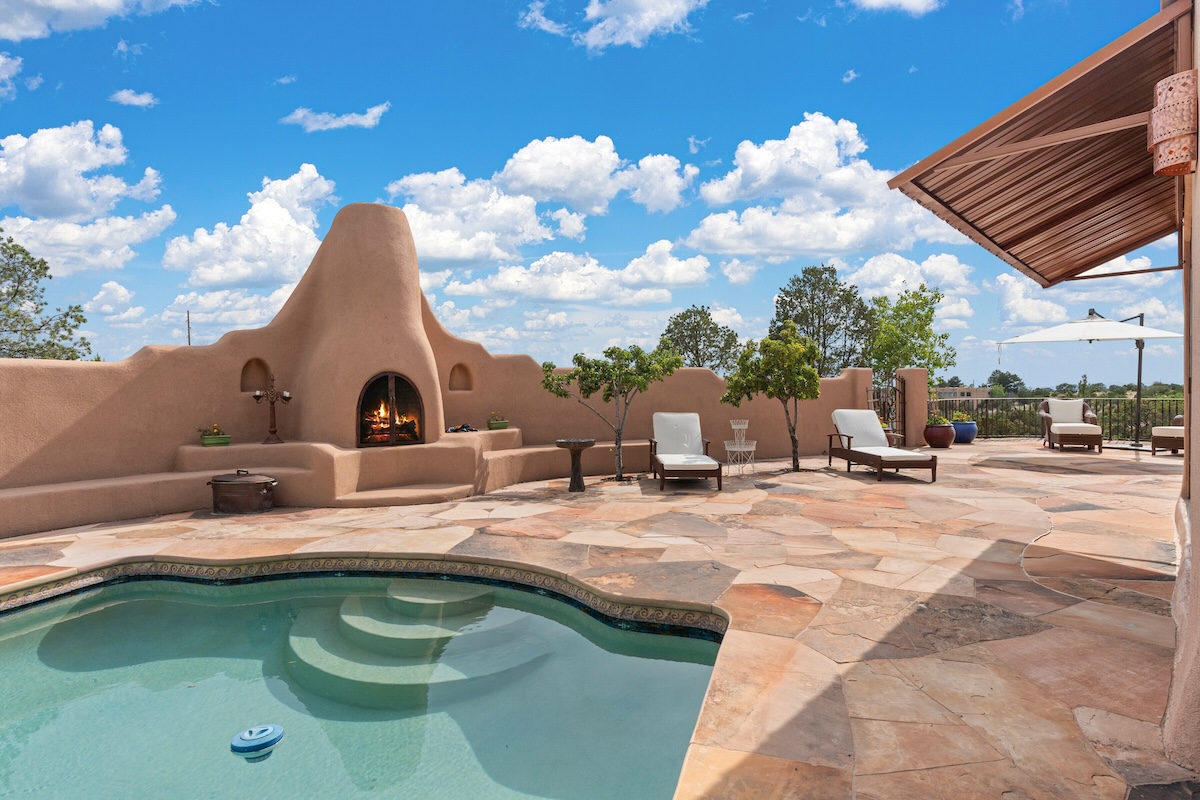 The pool area with a fire place at an adobe home.