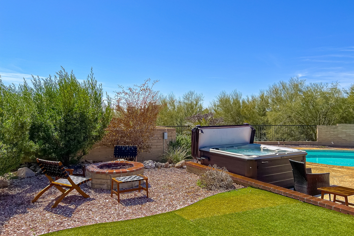 Backyard of a home with an outdoor firepit, hot tub, and swimming pool