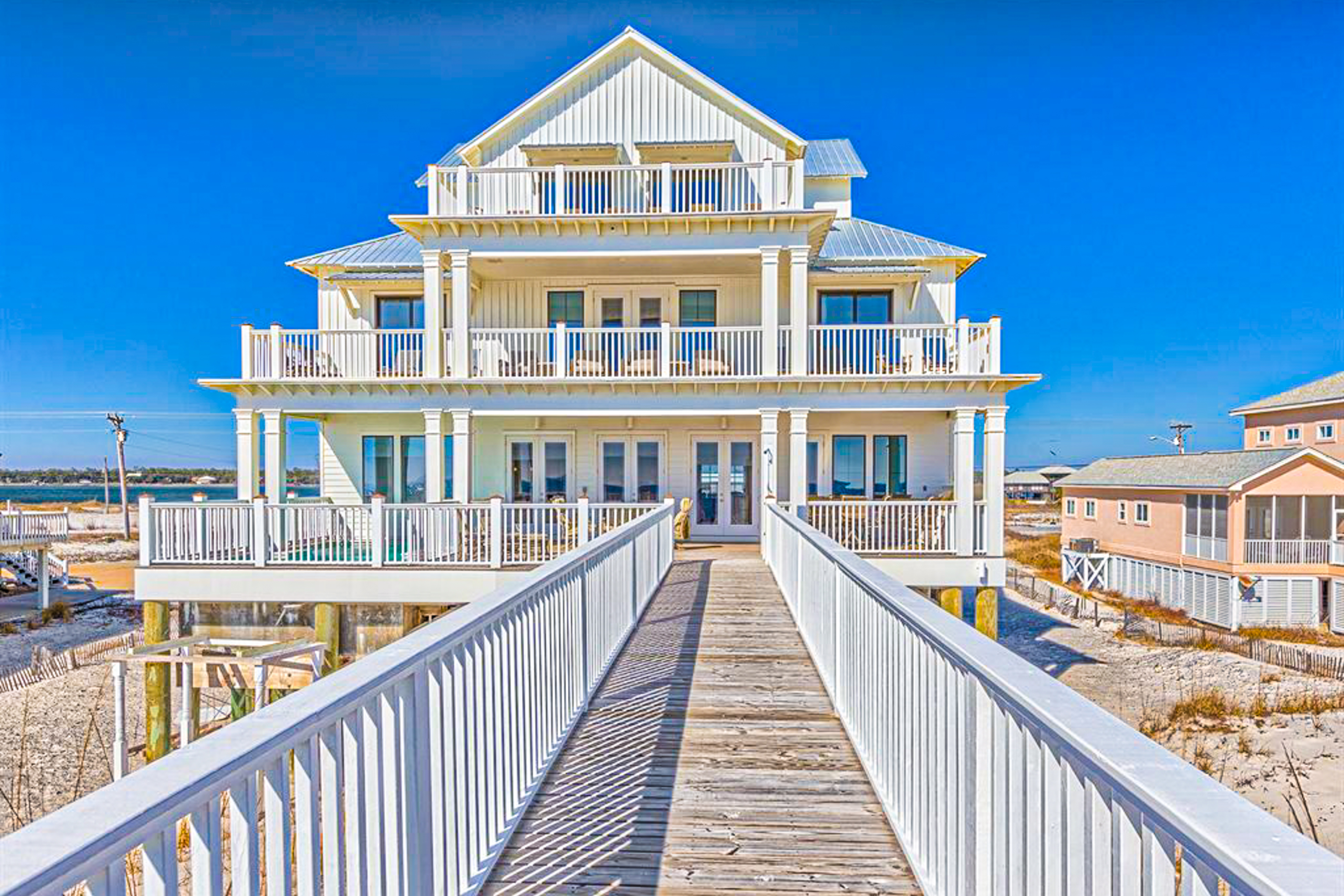 Three story white coastal home with a boardwalk in Gulf Shores, Alabama