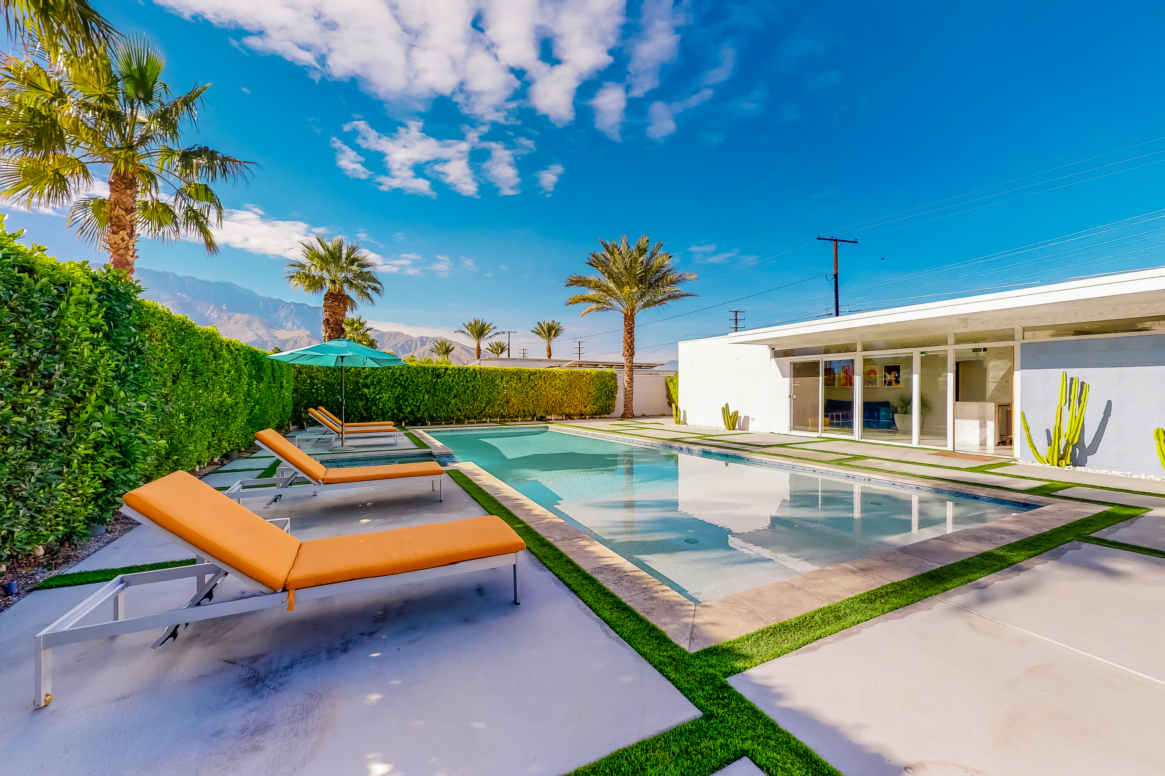 backyard of vacation rental in palm springs with private pool and orange lounge chairs