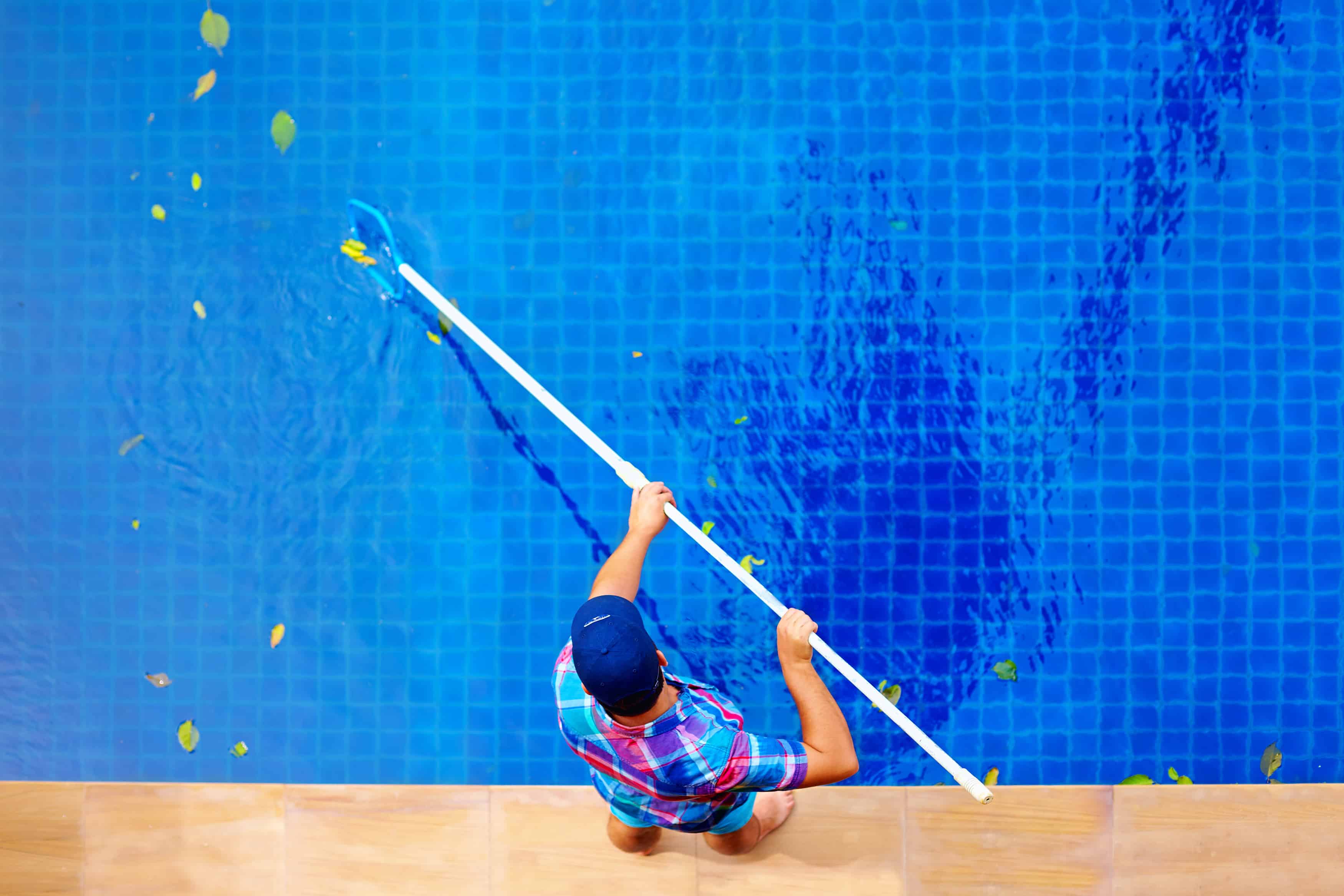 An employee cleaning leaves out of a pool