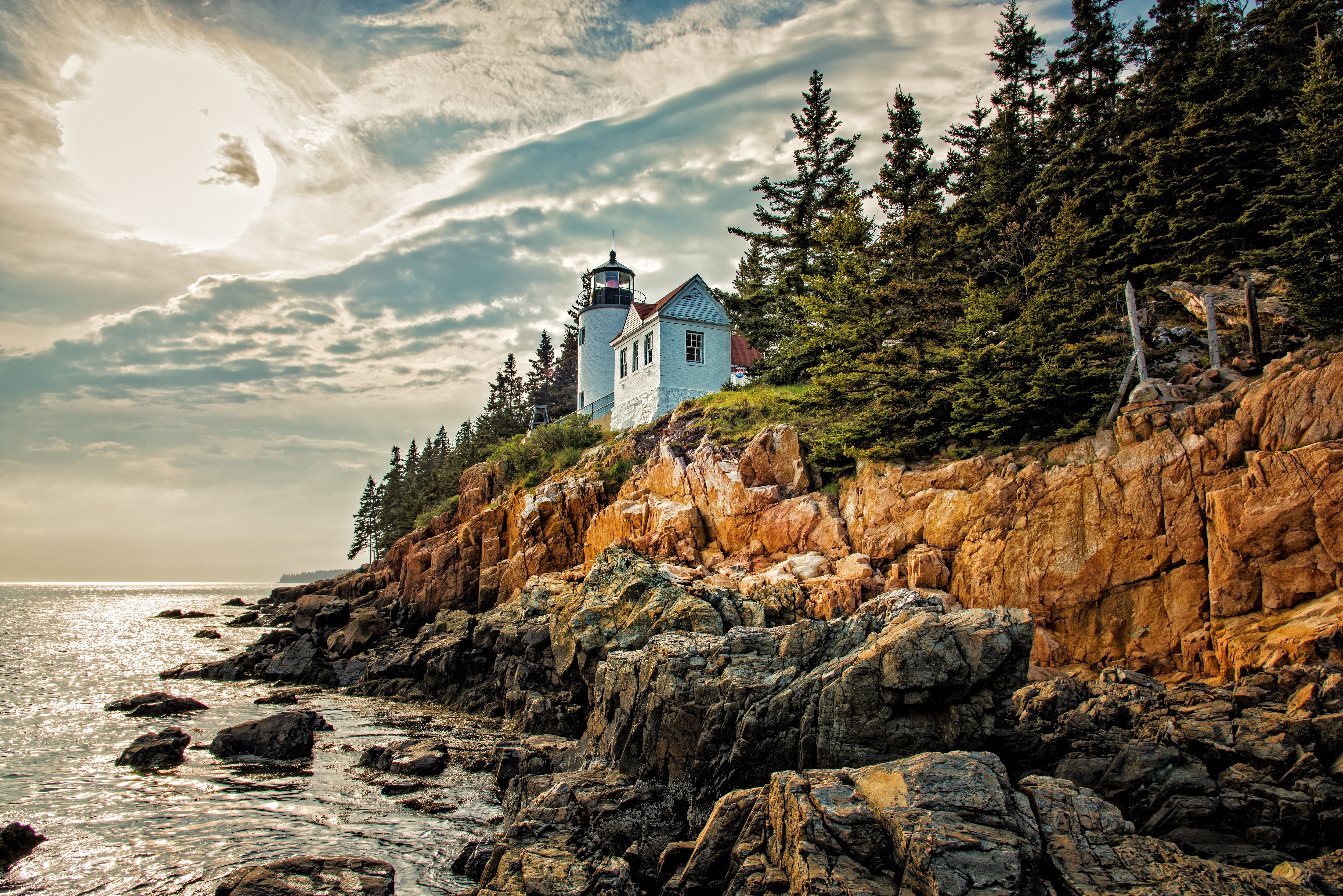 a lighthouse in acadia sits on the cliffs overlooking the ocean