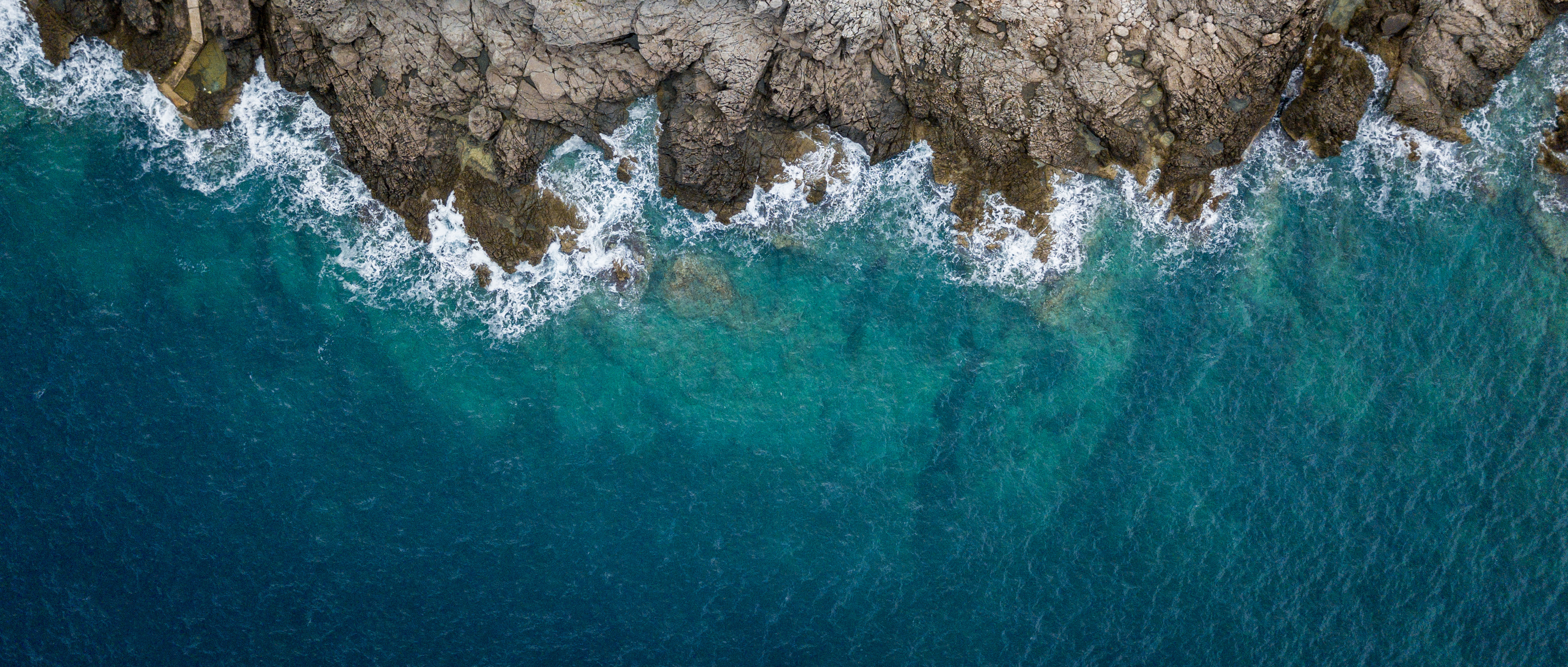 Aerial view of ocean washing up against rocks