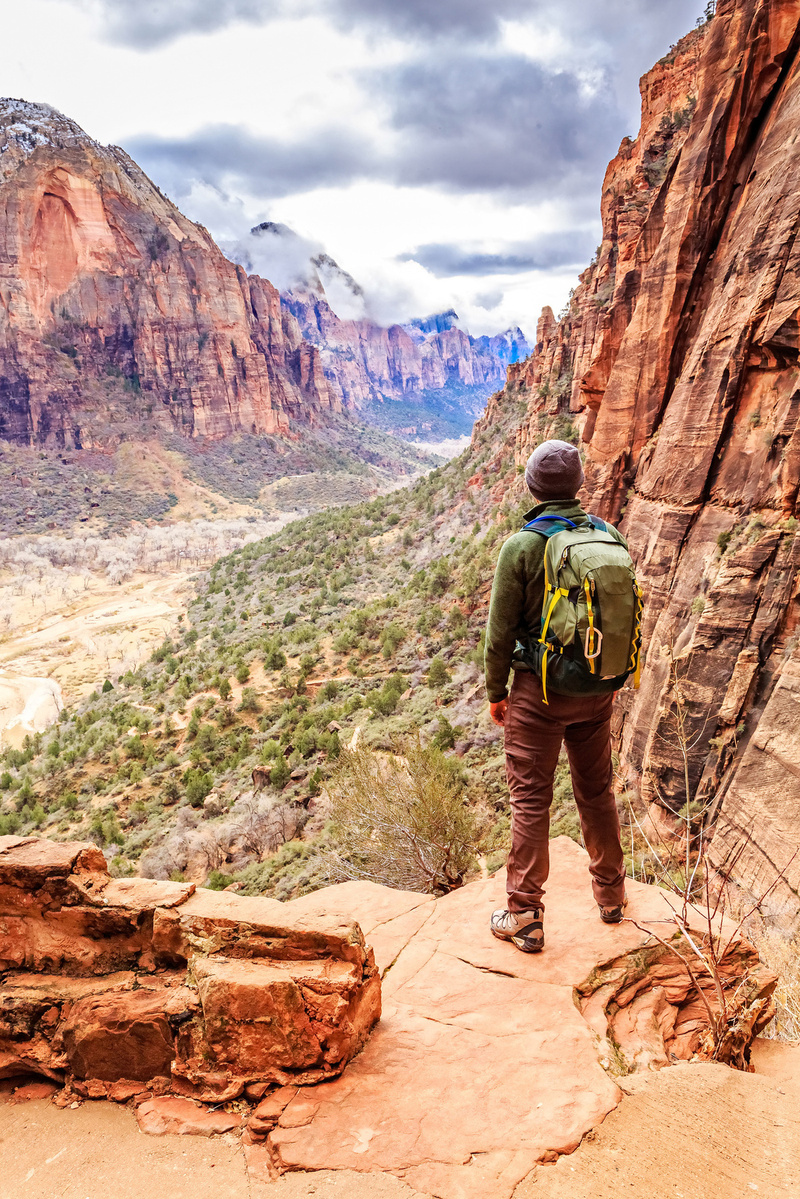 person hiking standing at an overlook with mountain valley view