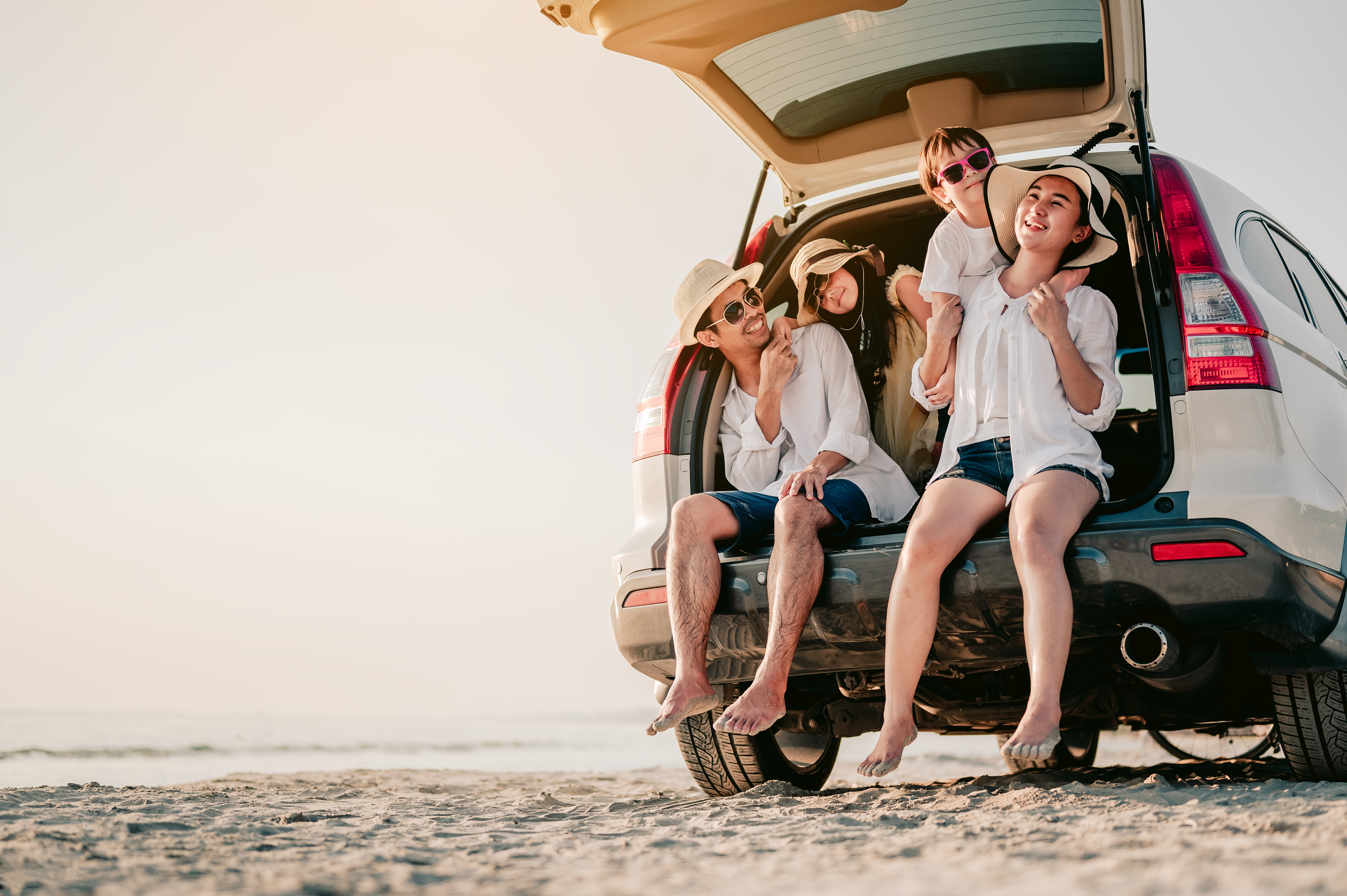 Family of four sitting in the trunk of a car at the beach