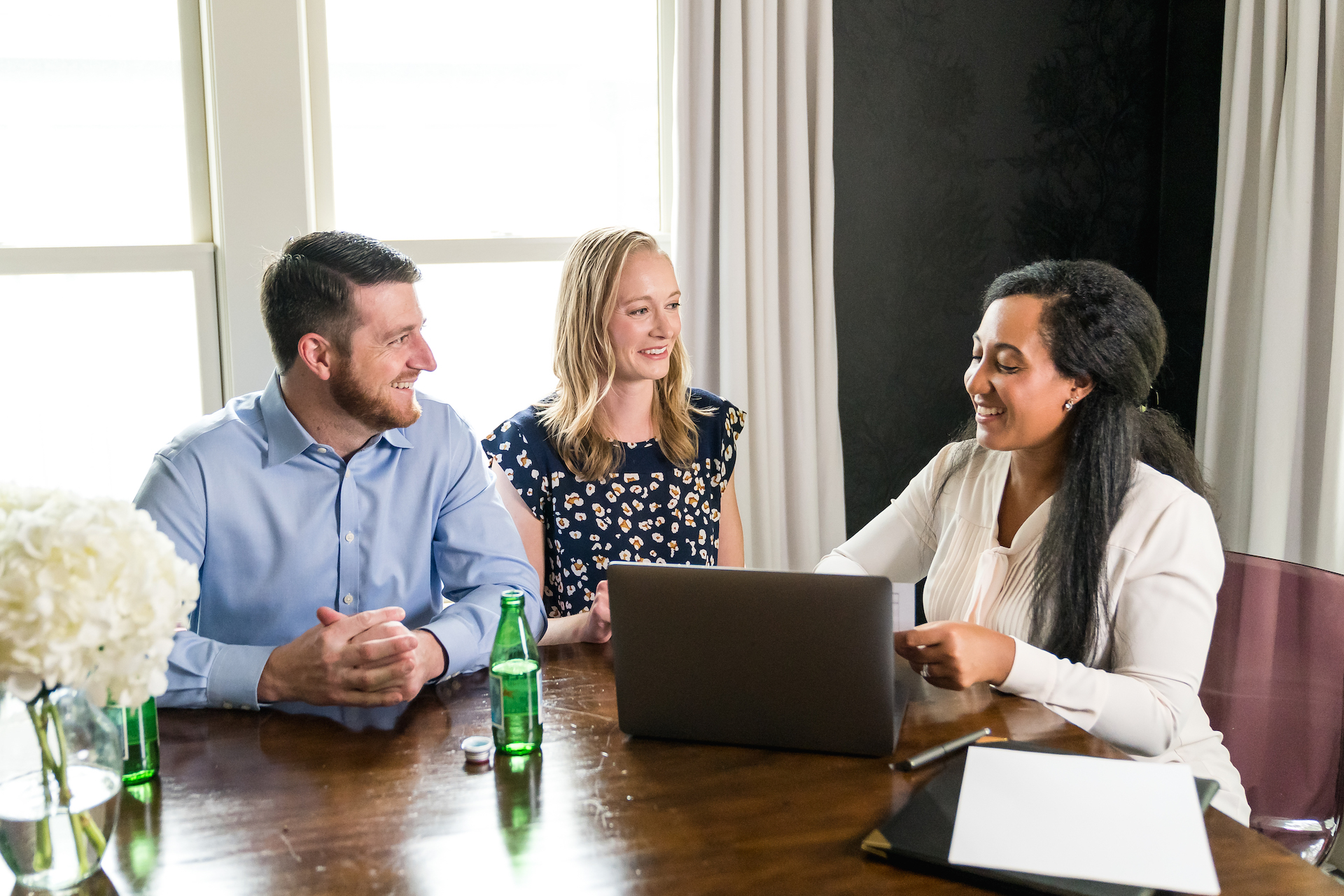 Three people discussing business at a table with a laptop.