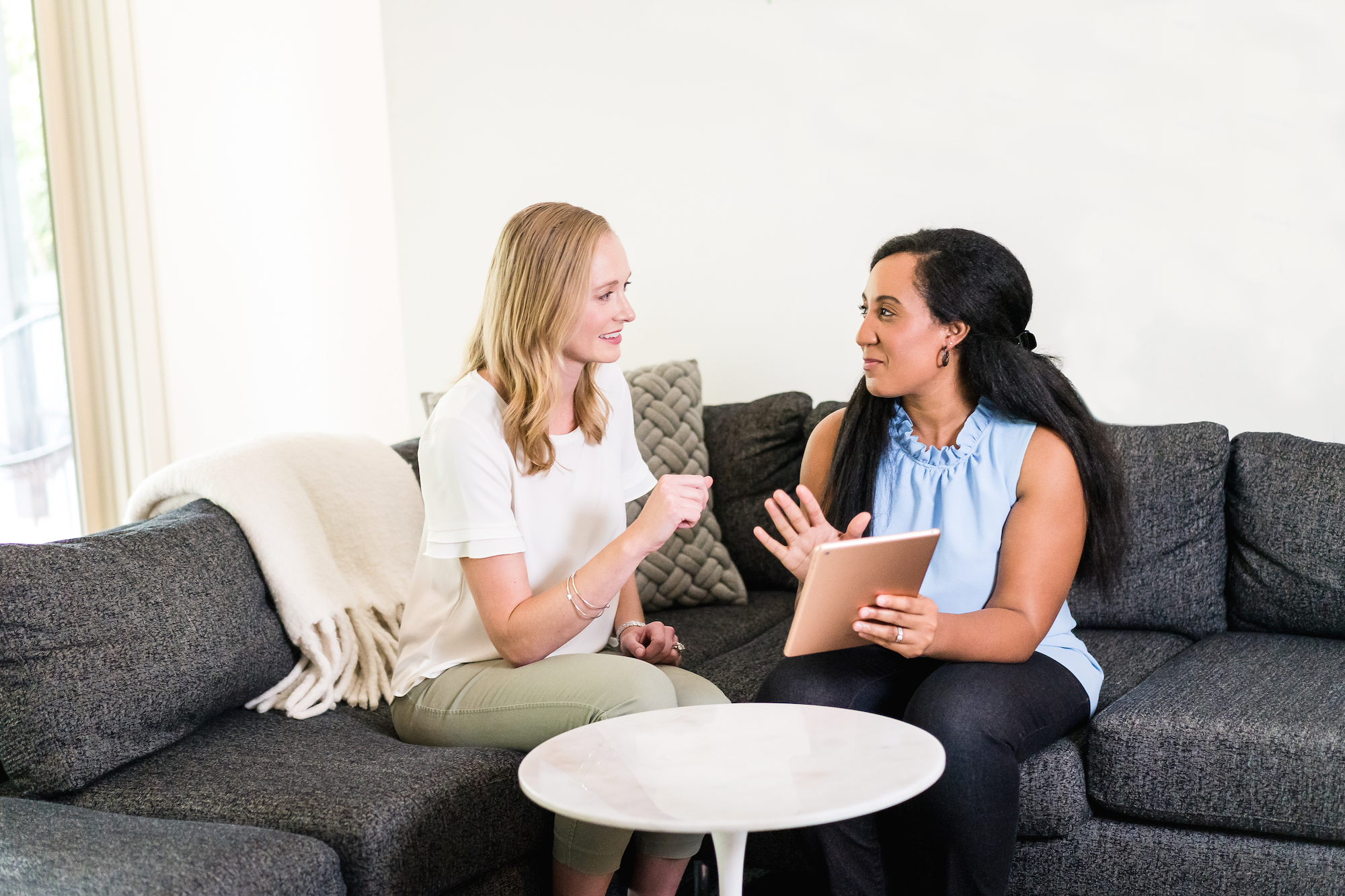 Two women using an iPad discussing vacation rentals.