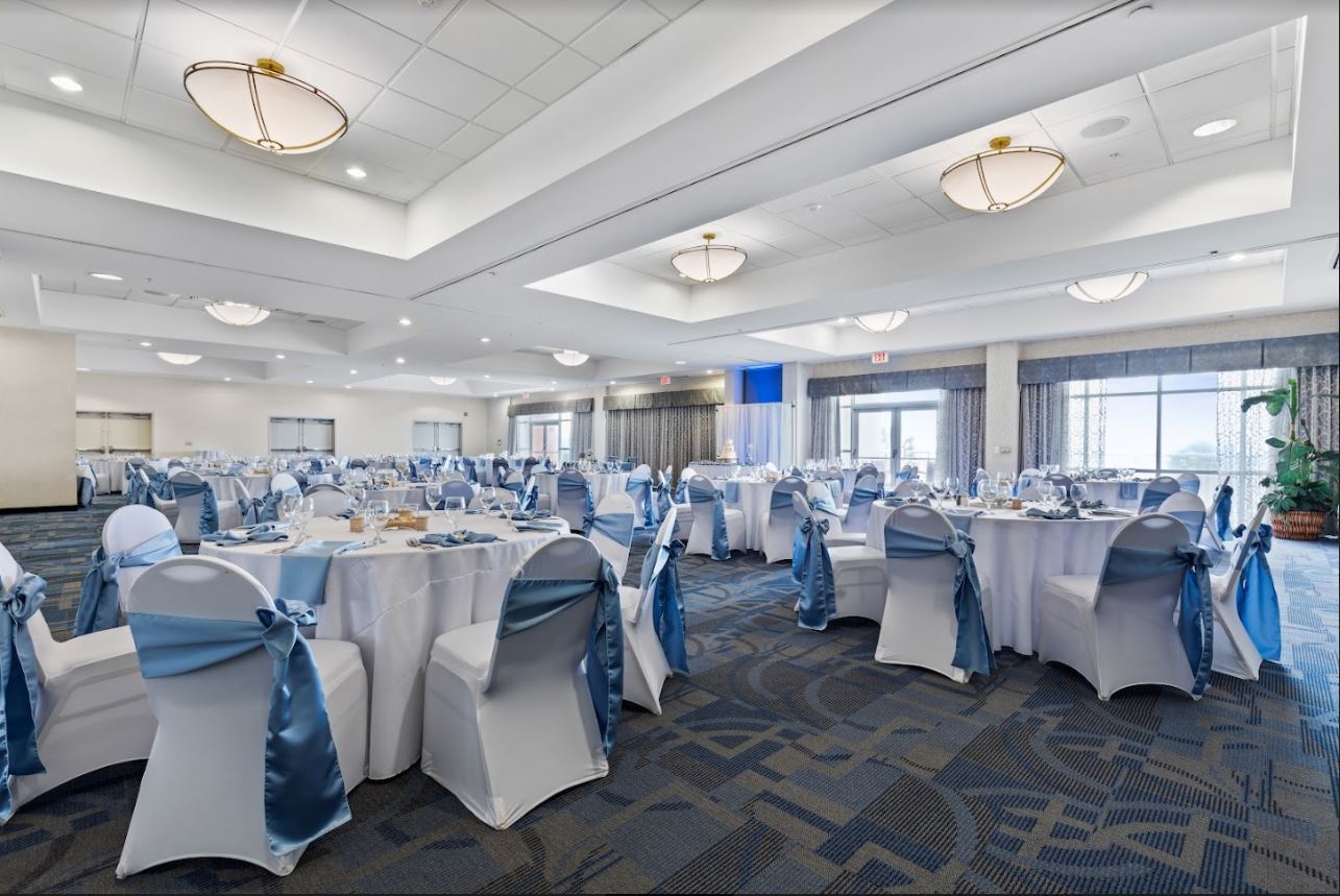 Inside Bay Watch Resort ballroom with tables and chairs in white fabric.