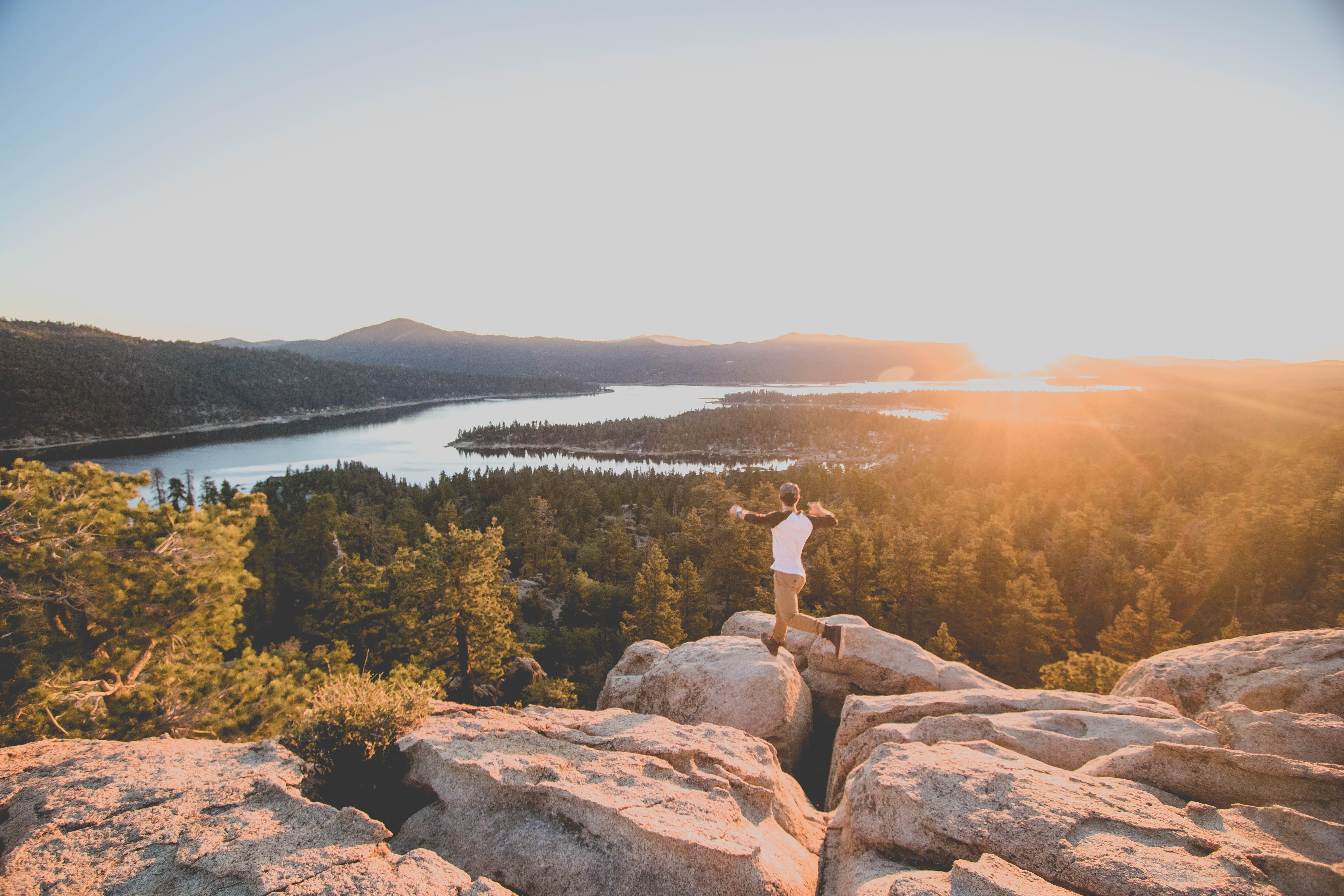 a man jumps across rocks to take in the amazing view in Big Bear during a hike