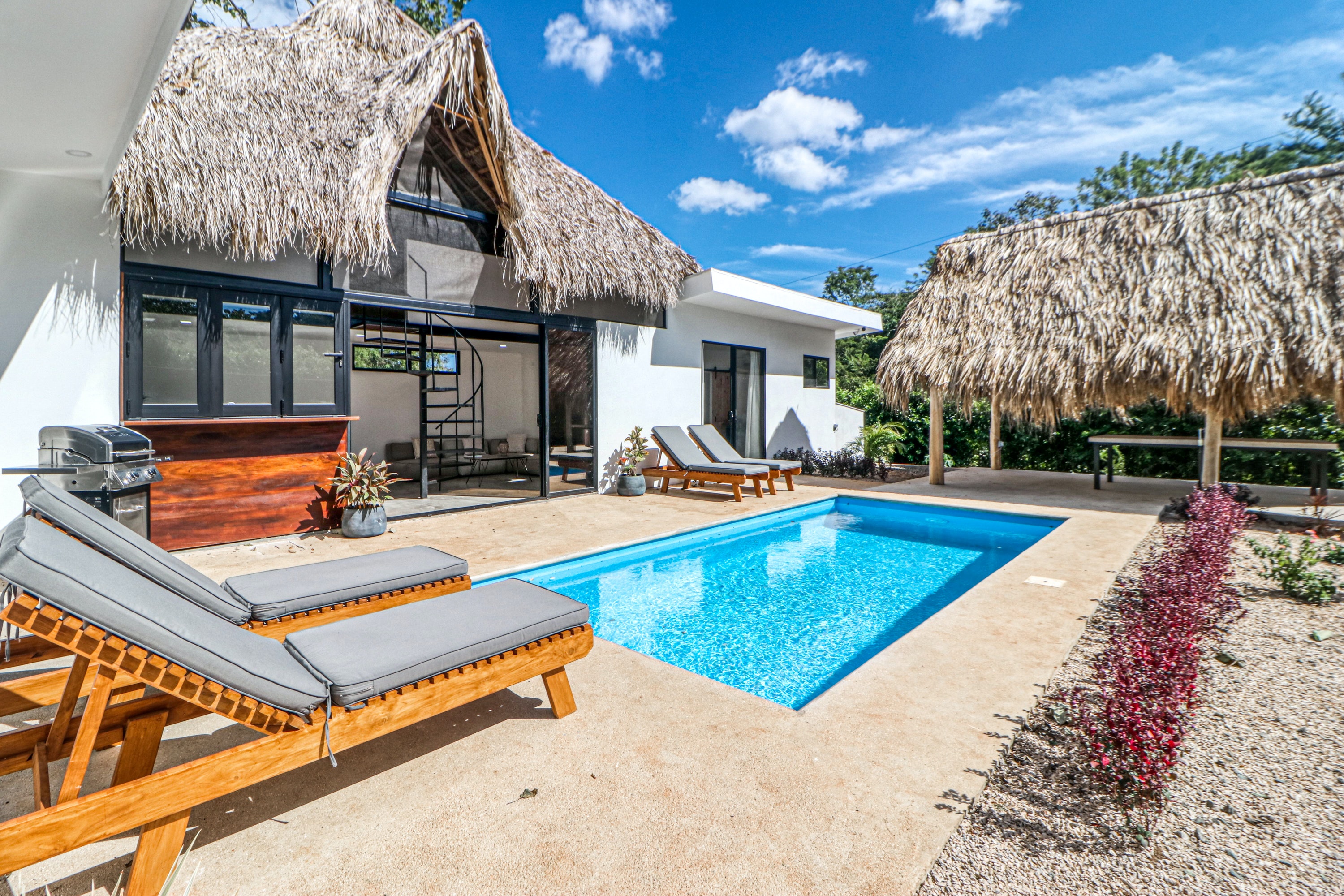 vacation rental with palm frond roofs and an outdoor pool