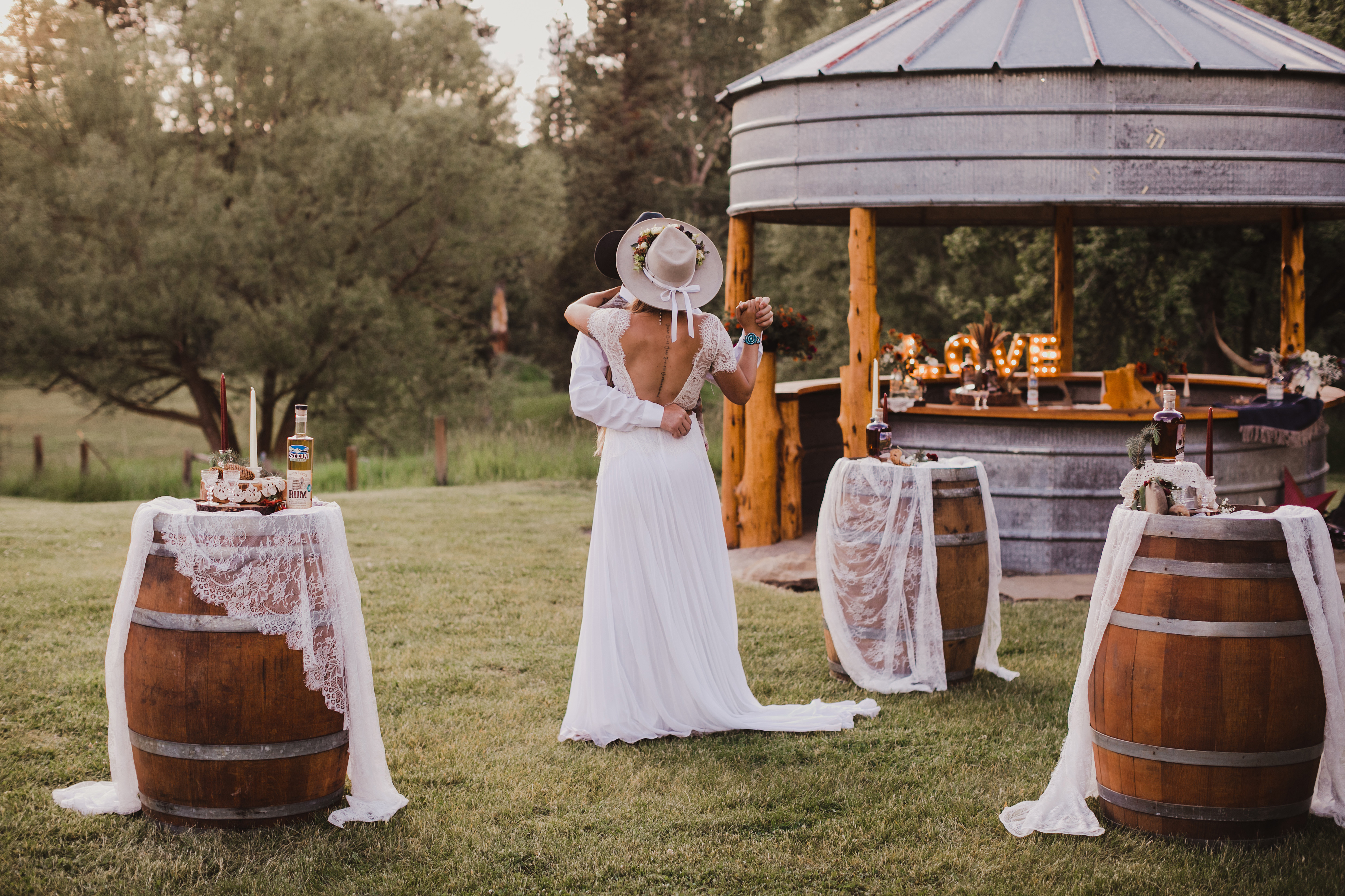 Couple dancing on the grass near an outdoor tin bar.