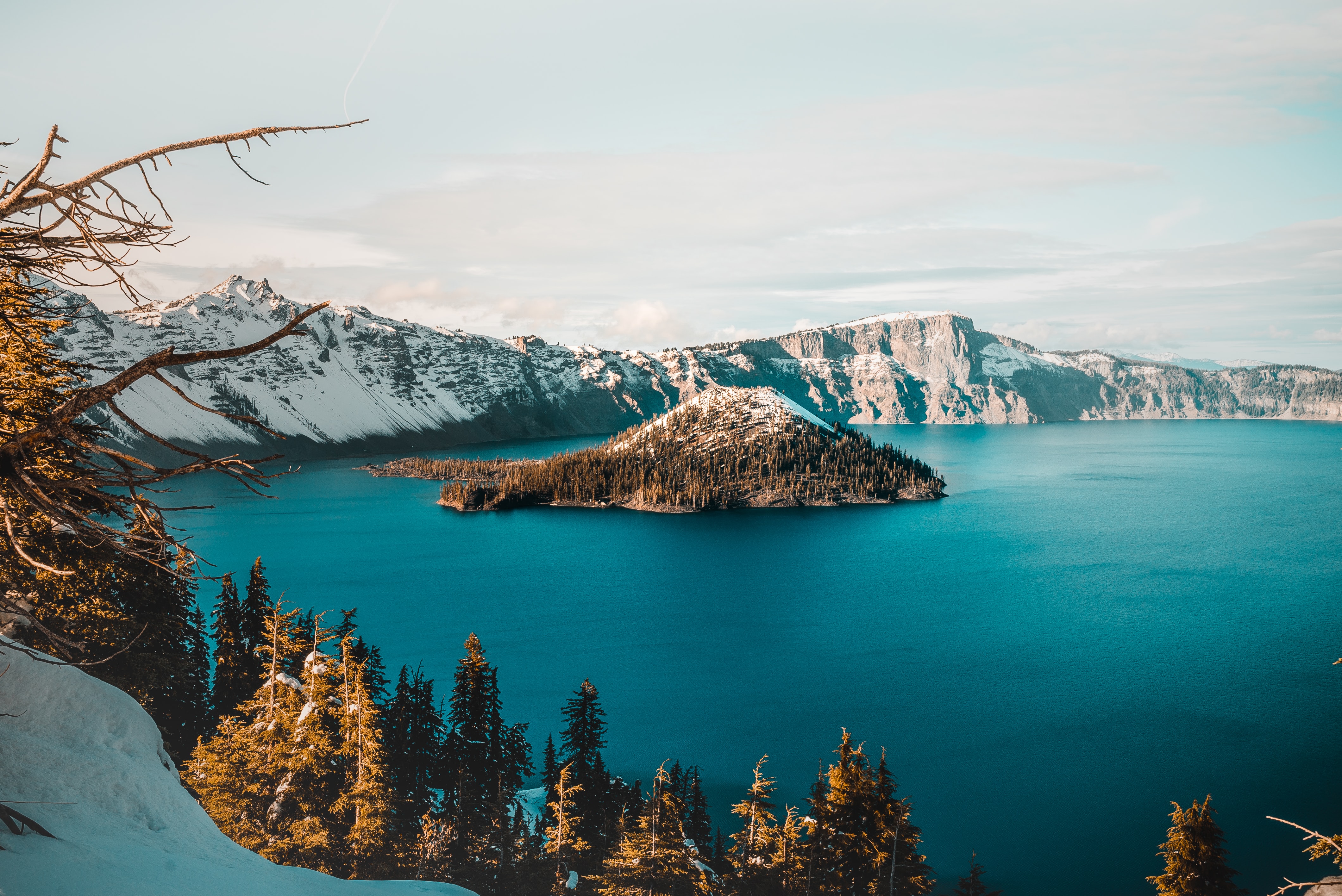 Crater lake during the winter with snow covering the outer rim and Wizard Island with a snowy peak