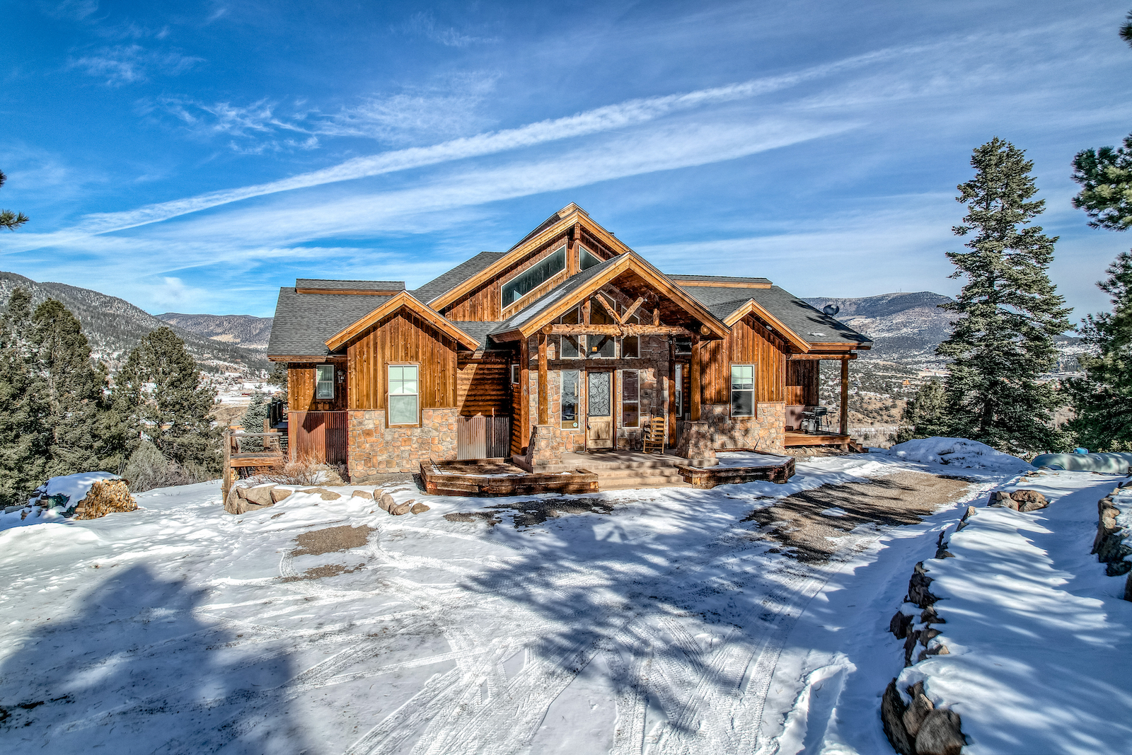 The exterior of a large cabin covered in snow overlooking the San Juan Mountains at a South Fork vacation rental.