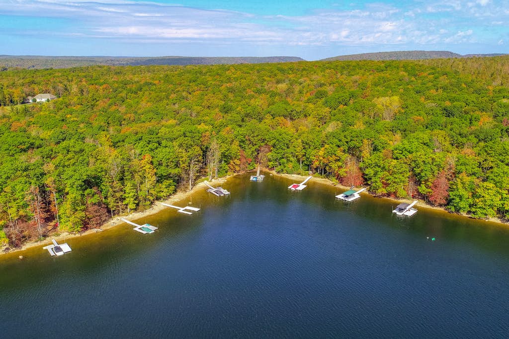 Large lake in the mountains with multiple boat docks and platforms in Deep Creek Lake, MD.