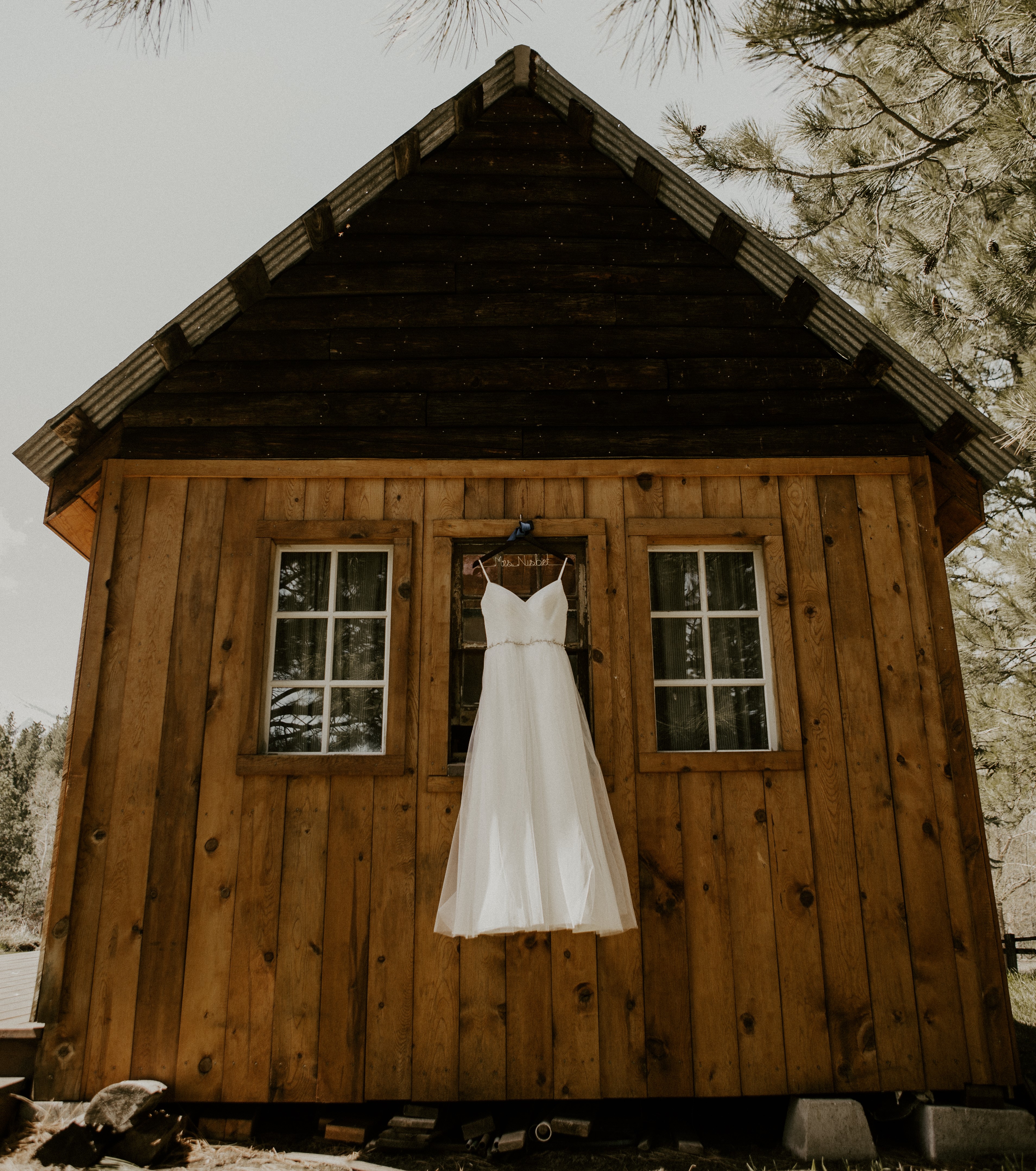 White wedding dress hanging from a window to a cabin