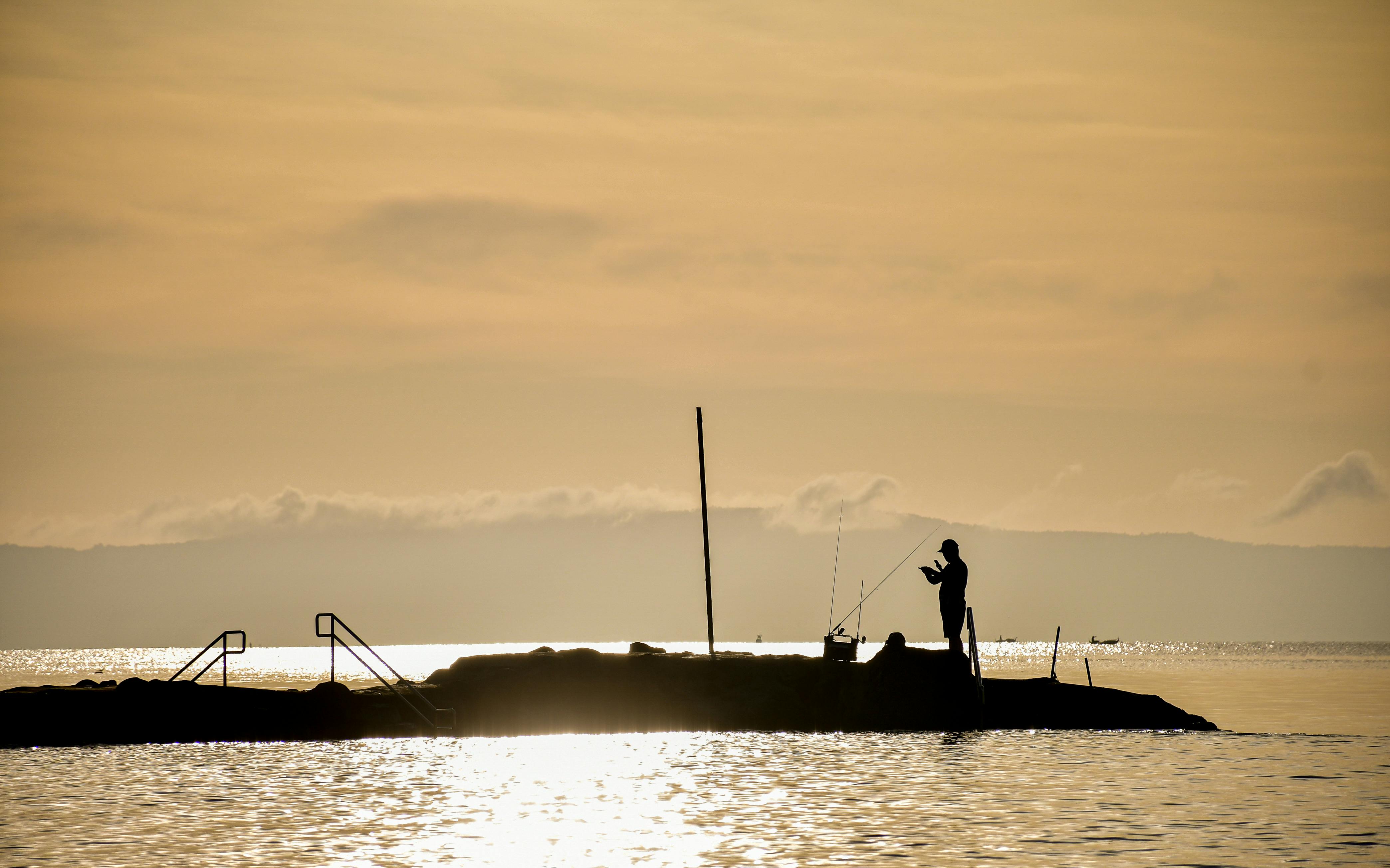 Man on a small piece of land fishing.