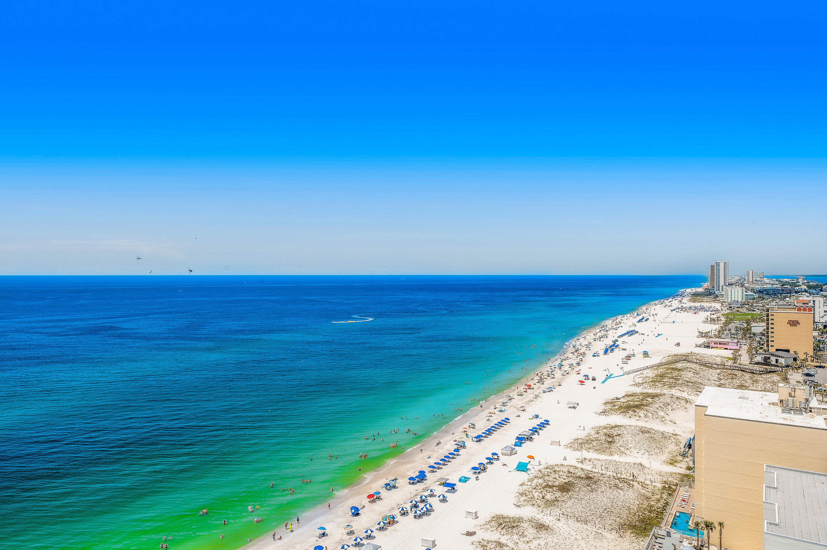 A drone shot of the coastline lined with vacationers in Gulf Shores, AL.