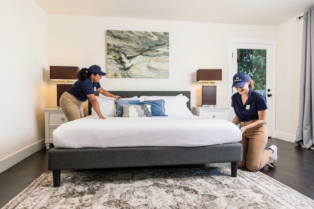 Two women making a bed.