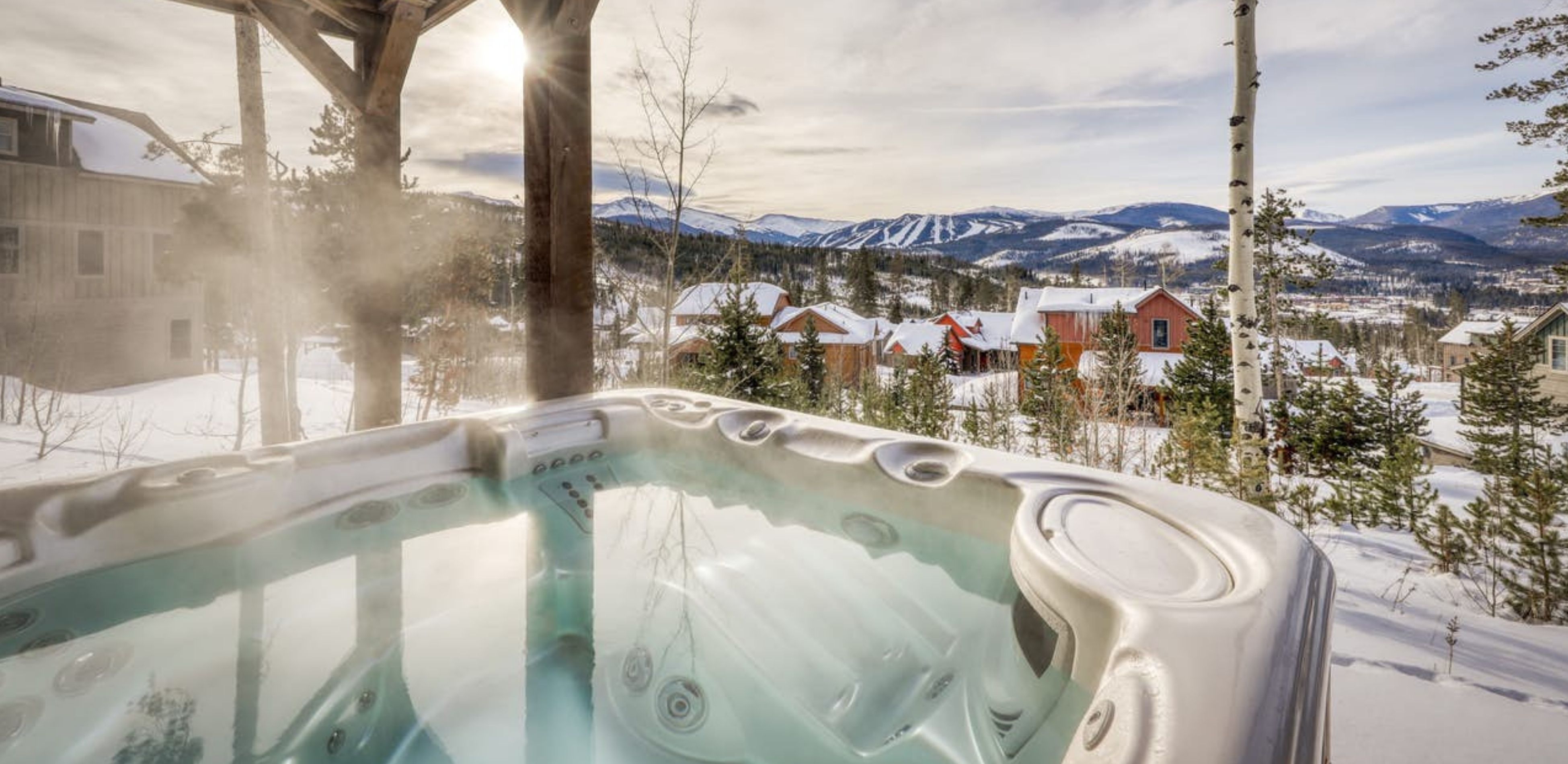 steamy hot tub with snow covered mountain views